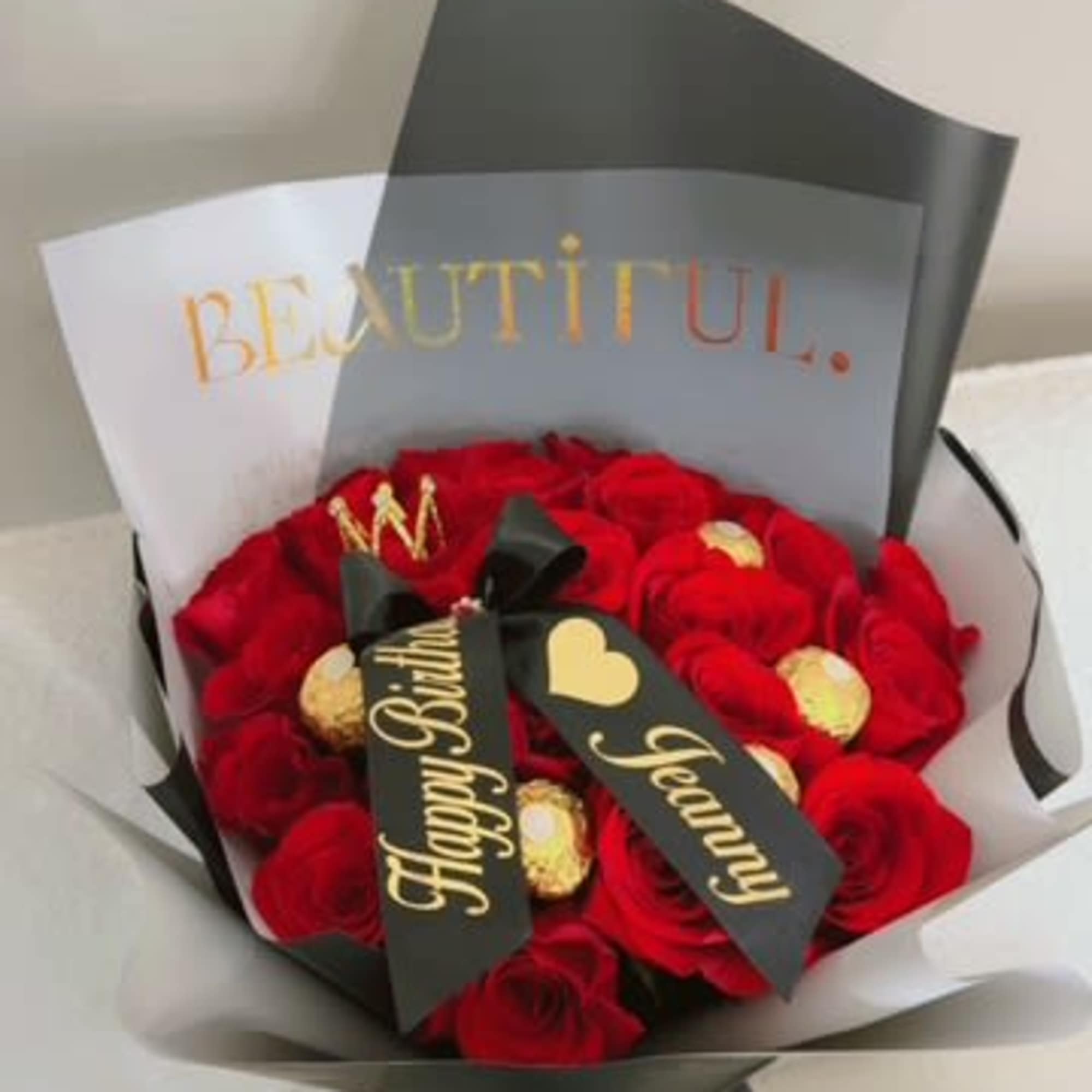 Bouquet of red roses with gold-wrapped chocolates and birthday ribbons
