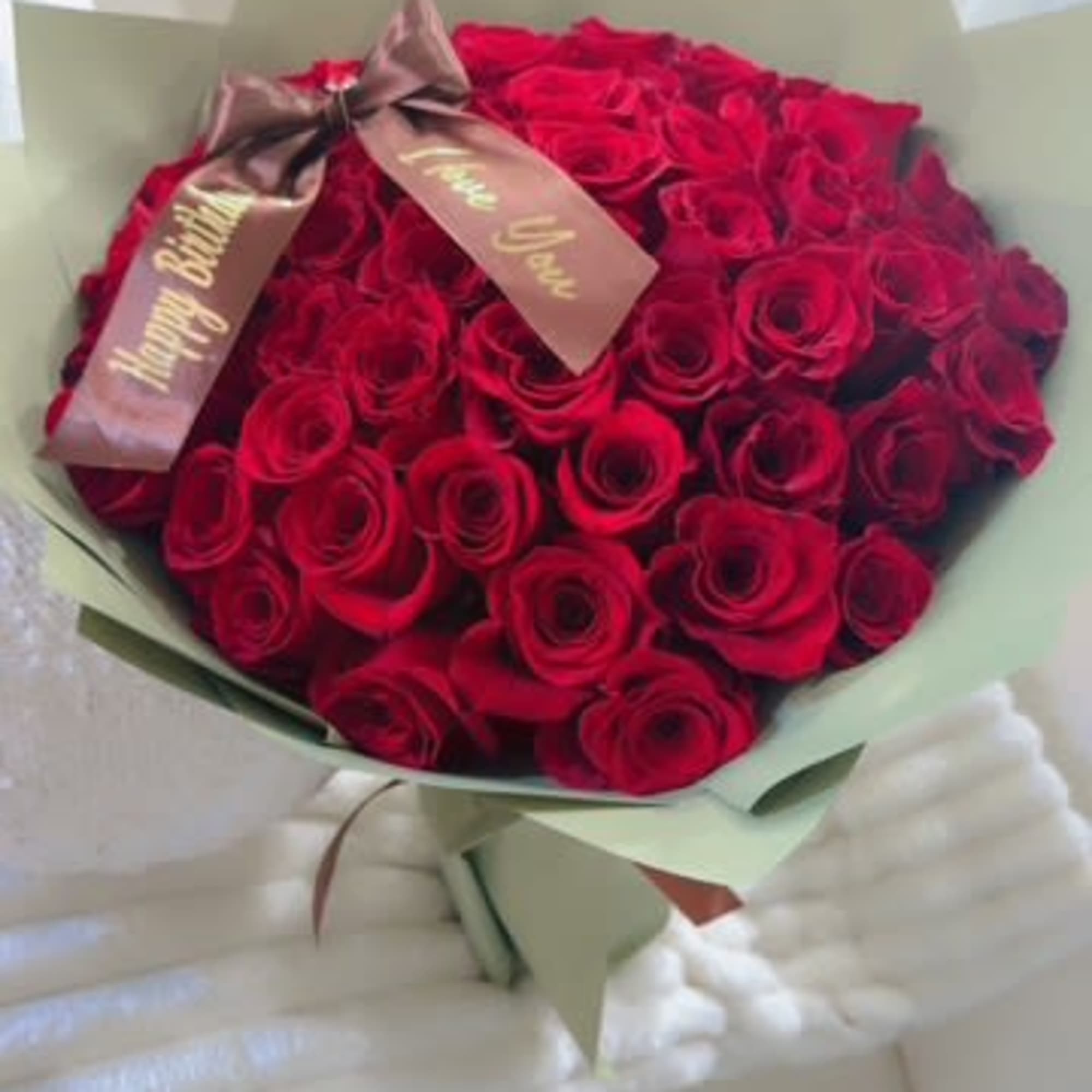Bouquet of red roses wrapped in pale green paper with a ribbon