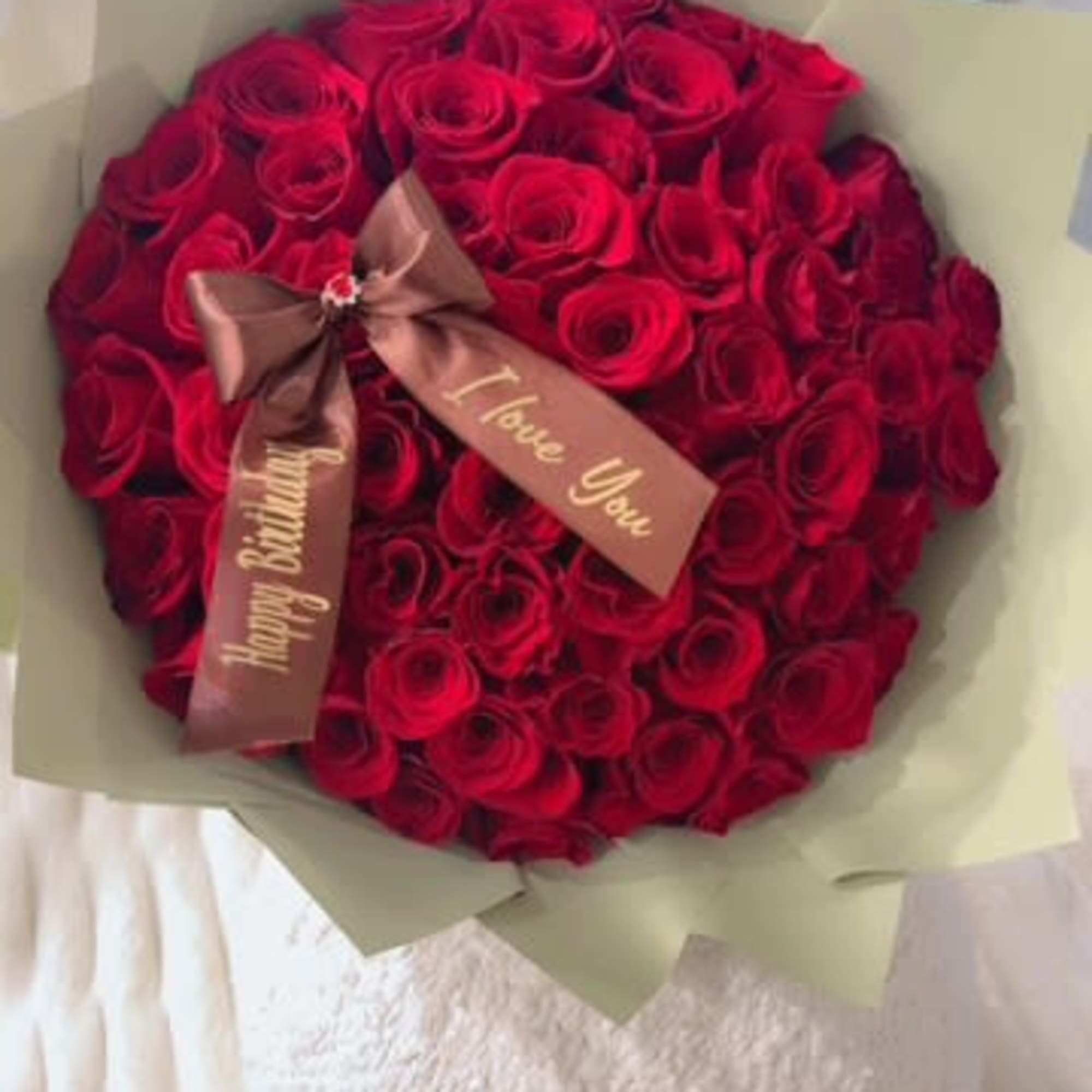 Bouquet of red roses wrapped in pale paper with a ribbon