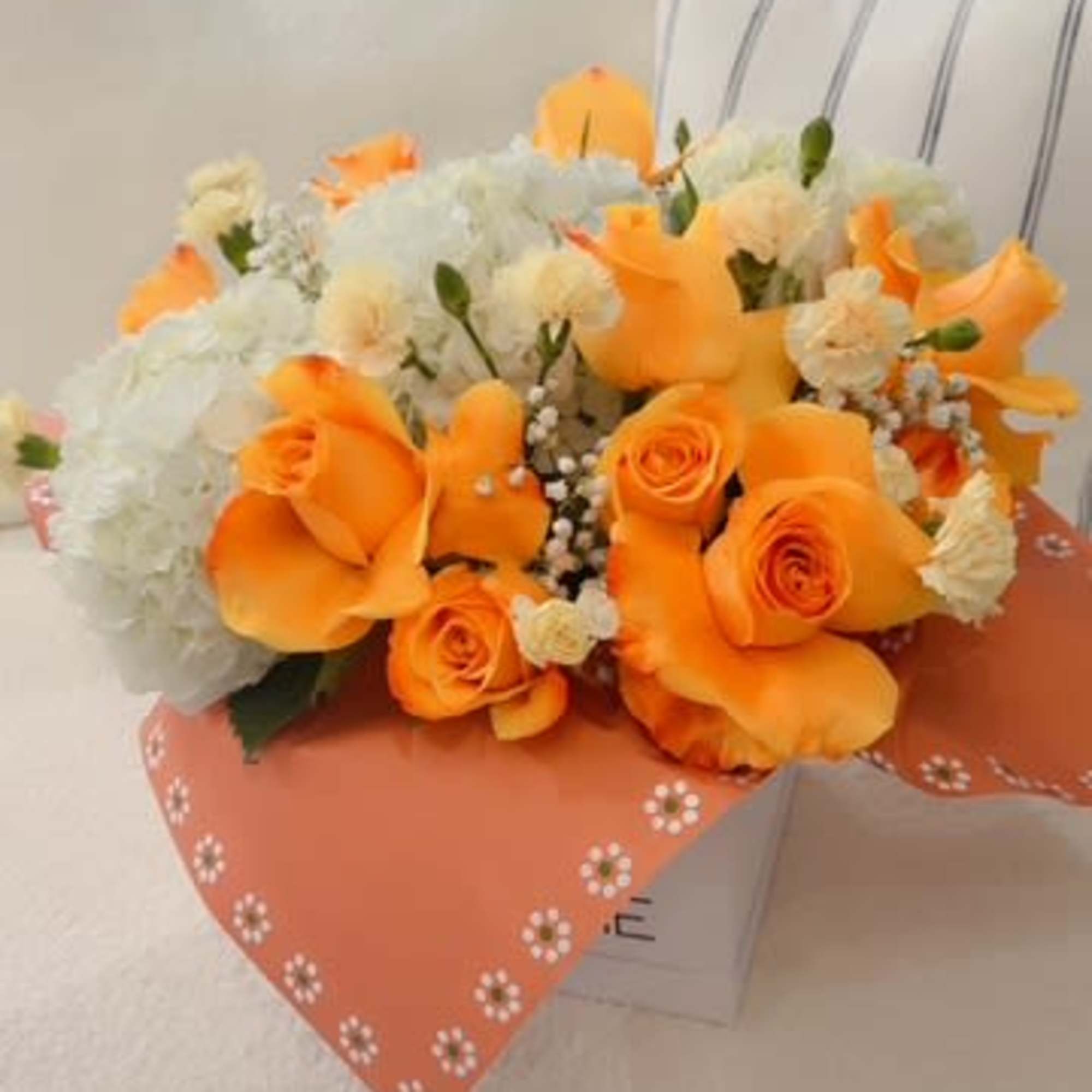 Orange roses and white flowers in a wrapped bouquet