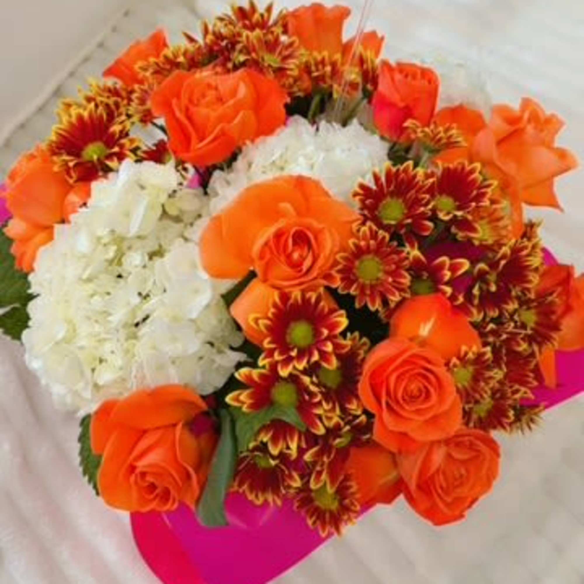 Orange roses and red-yellow chrysanthemums with white hydrangea in a pink wrap