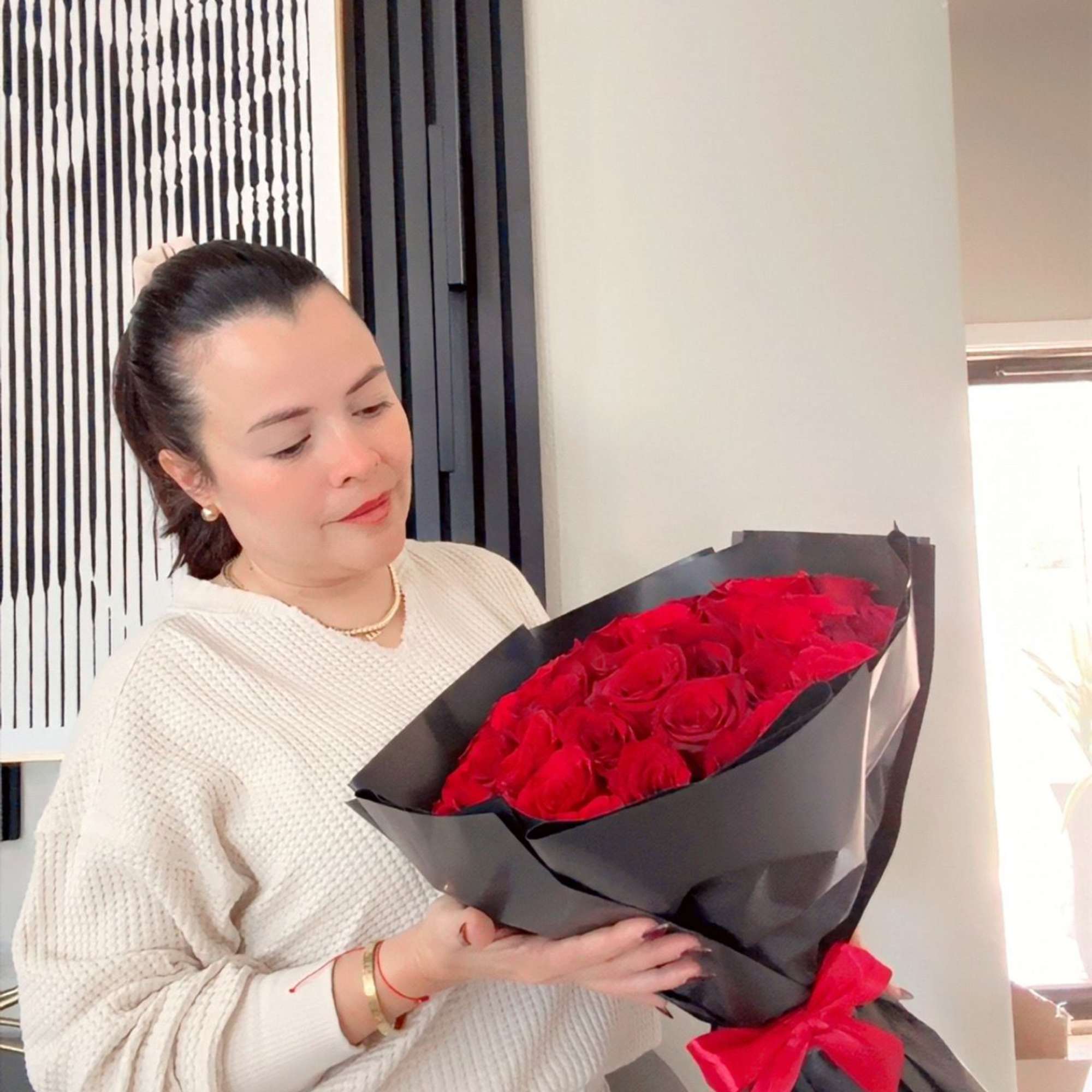 Woman holding a bouquet of red roses wrapped in black paper
