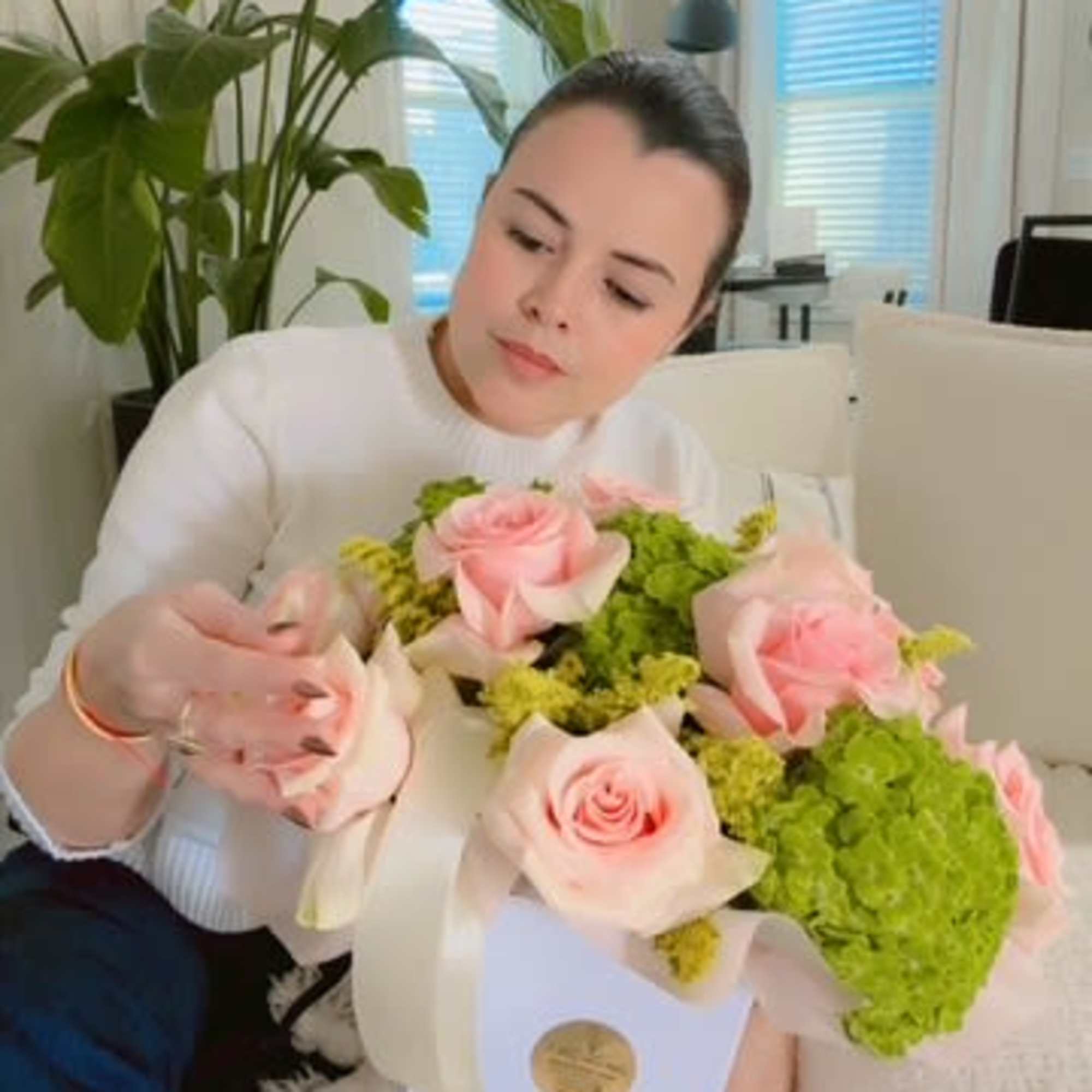 Woman holding a bouquet of pink roses and green hydrangeas in a white box
