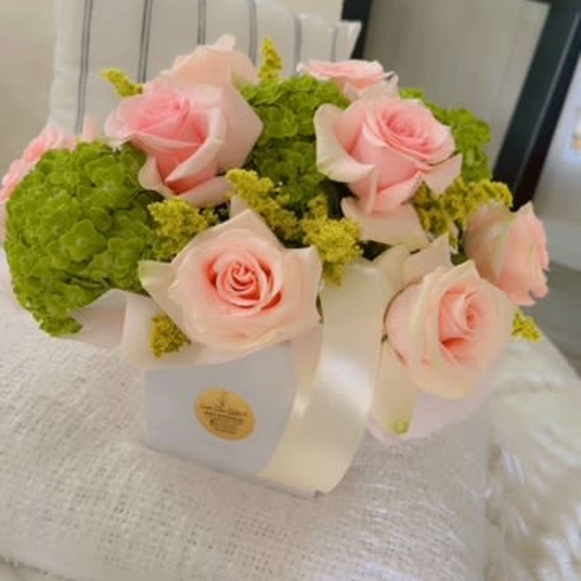 Pink roses and green hydrangeas arranged in a white box