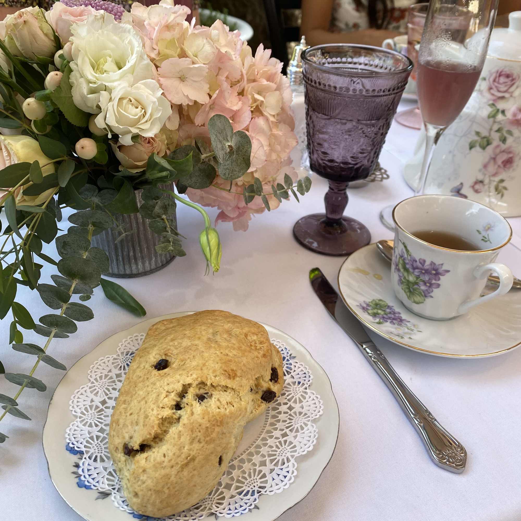 Pastel floral centerpiece in a metal vase on a tea table