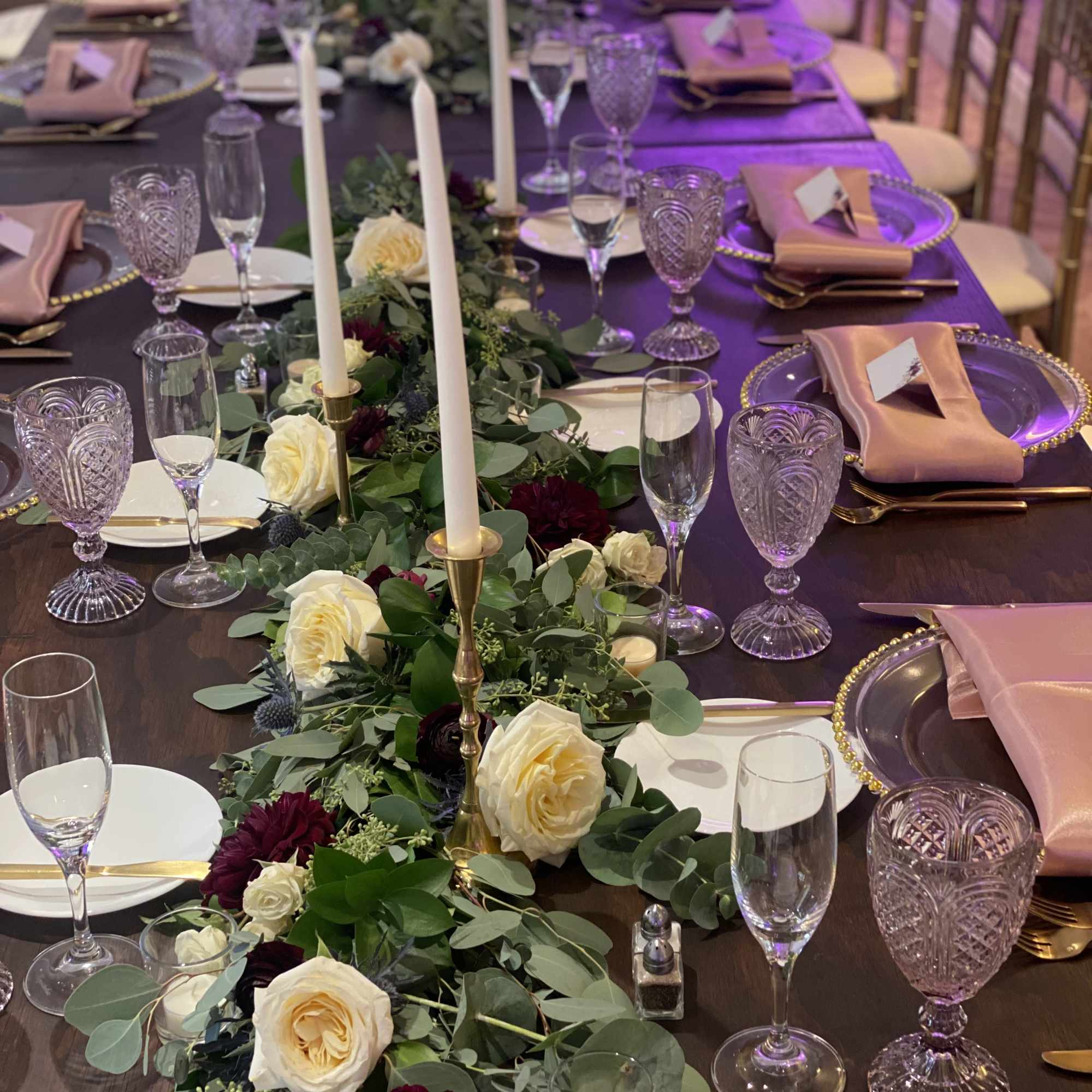 Long floral table centerpiece with white and burgundy roses on a banquet table