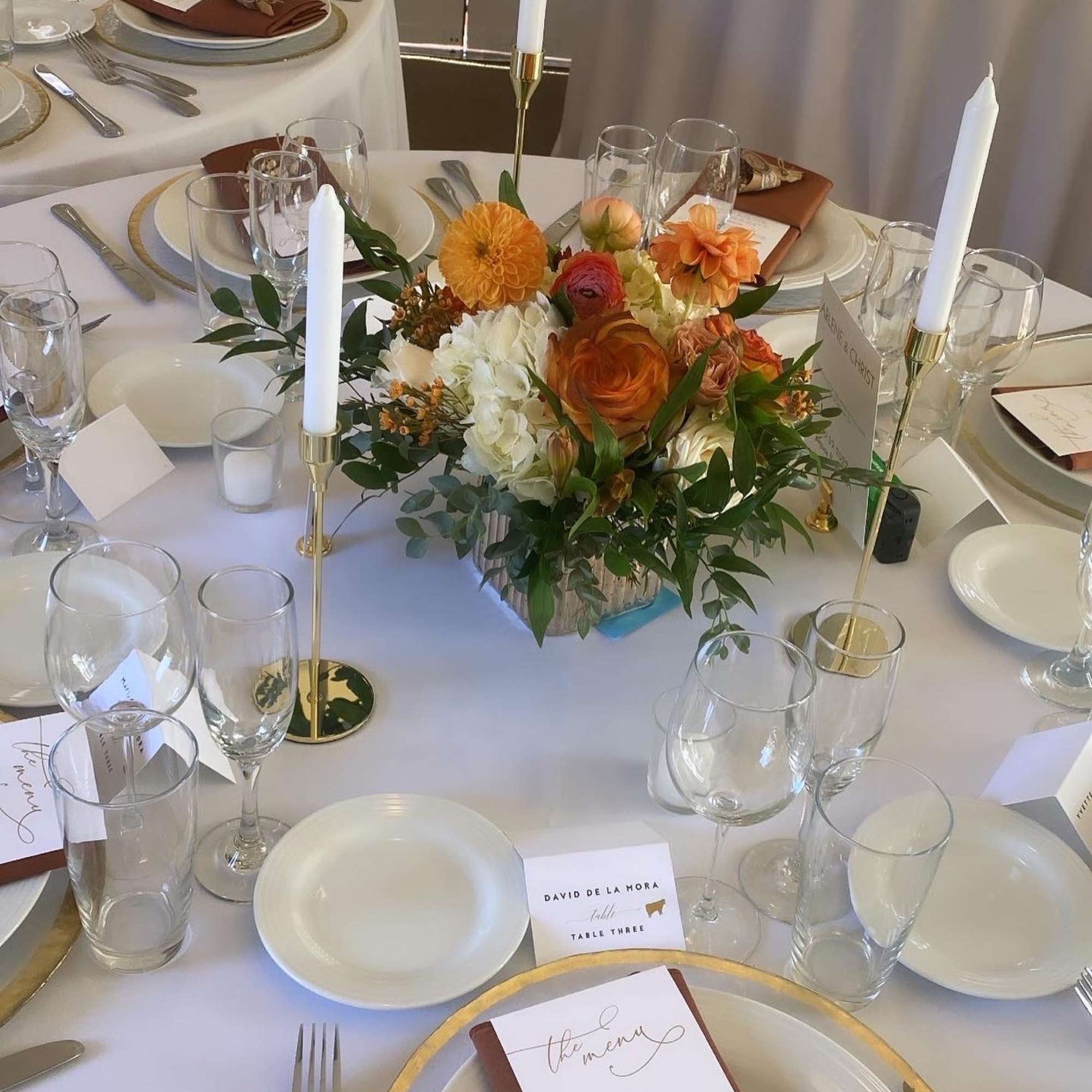 Floral centerpiece on a round banquet table with candles and place settings