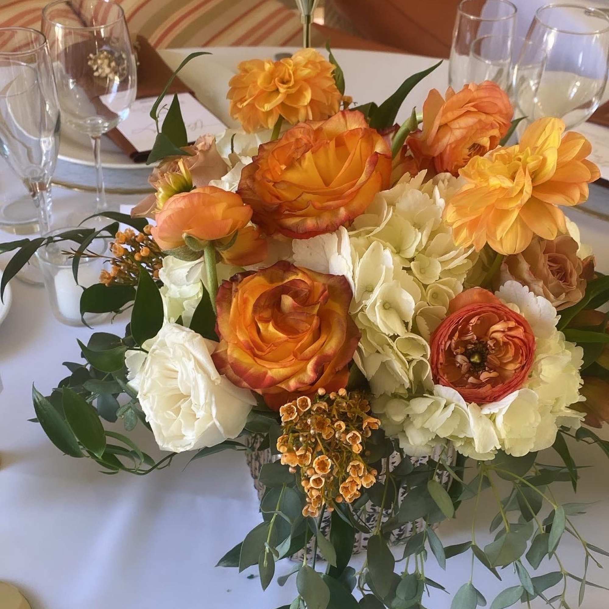 Orange and white floral centerpiece in a low vase on a table