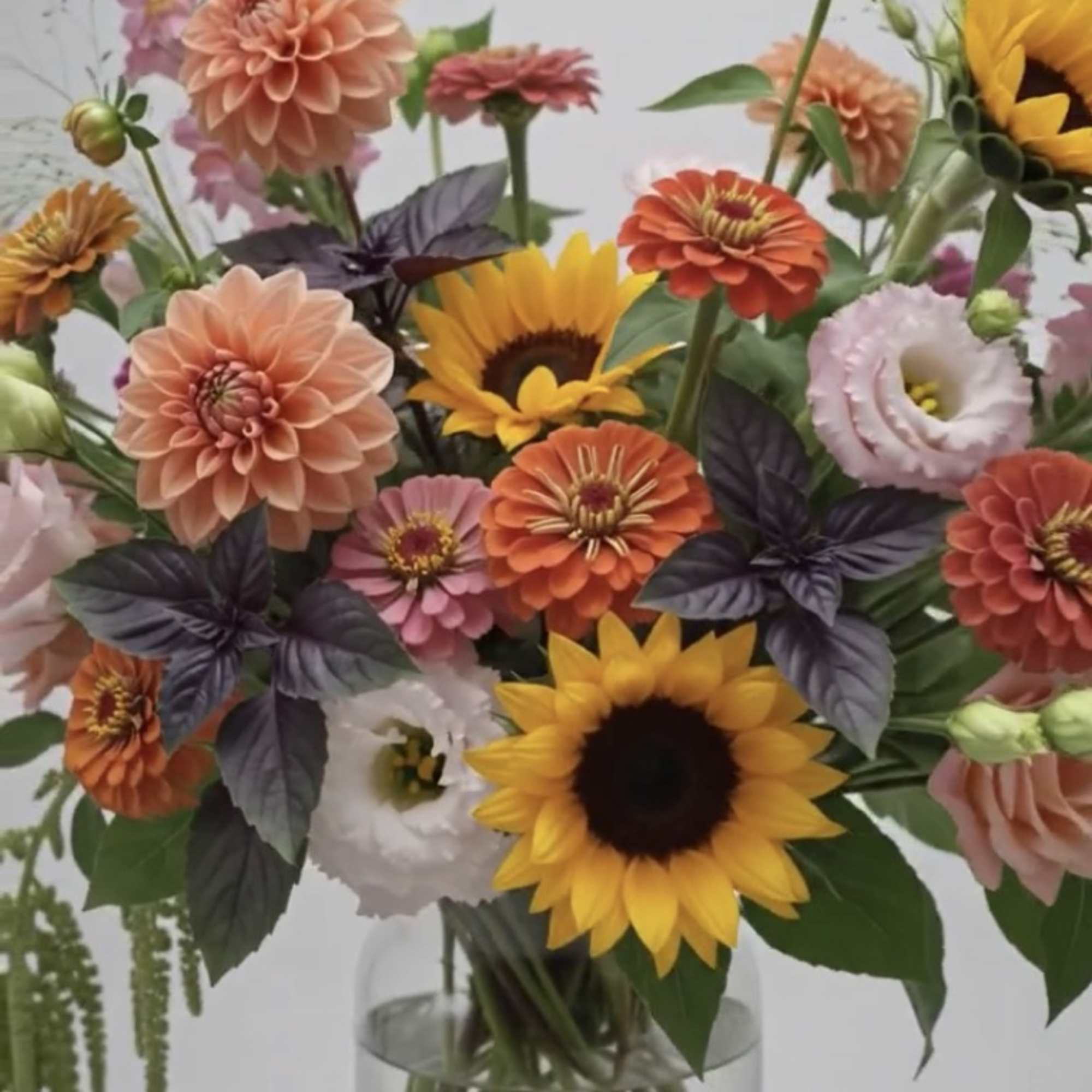 Mixed bouquet of sunflowers, dahlias, and lisianthus in a clear glass vase