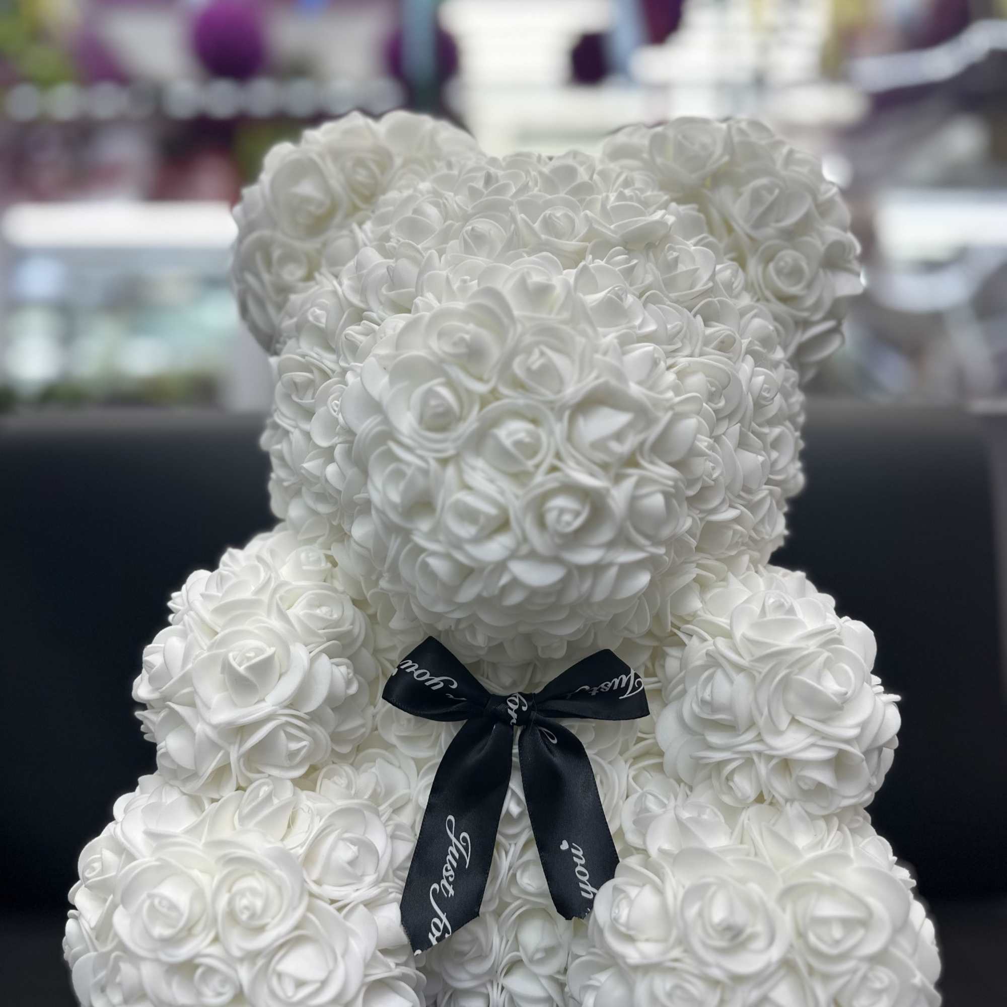 White rose teddy bear with a black ribbon bow
