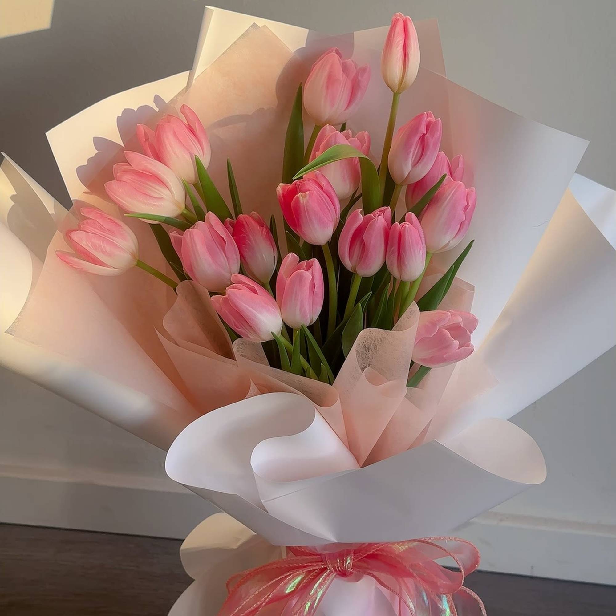 Pink tulip bouquet wrapped in white and blush paper with a pink ribbon