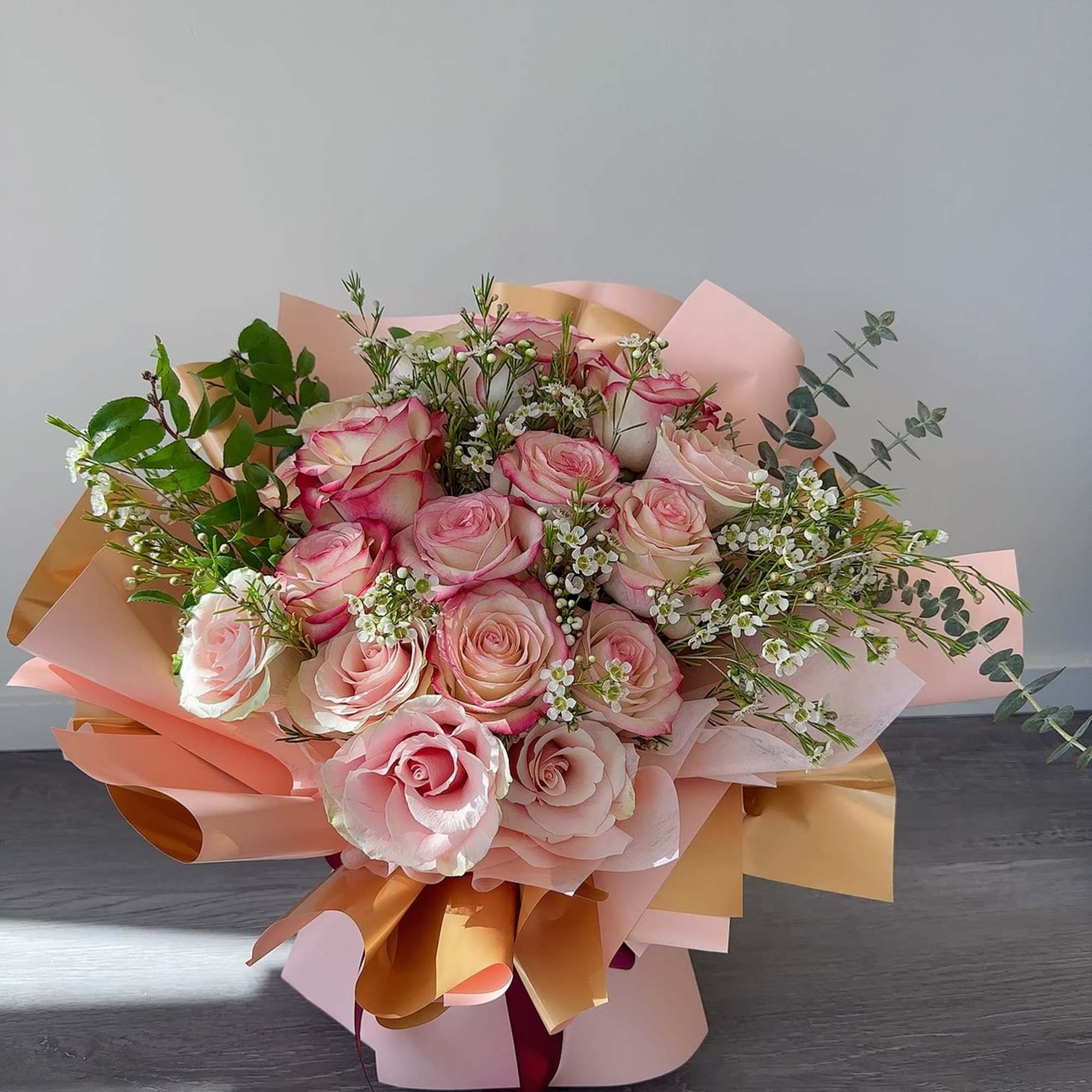 Pink and cream rose bouquet wrapped in peach paper