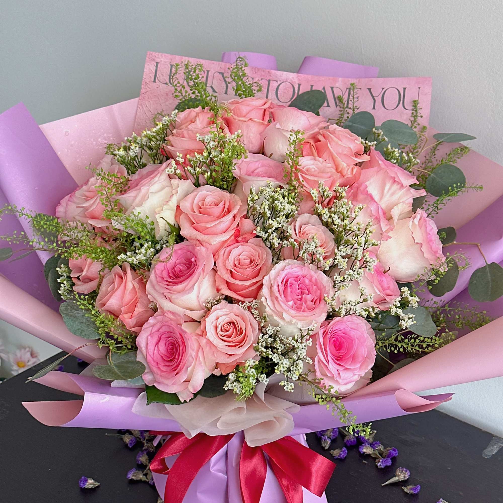 Pink rose bouquet wrapped in lavender paper with a red ribbon, photo 2 of 2