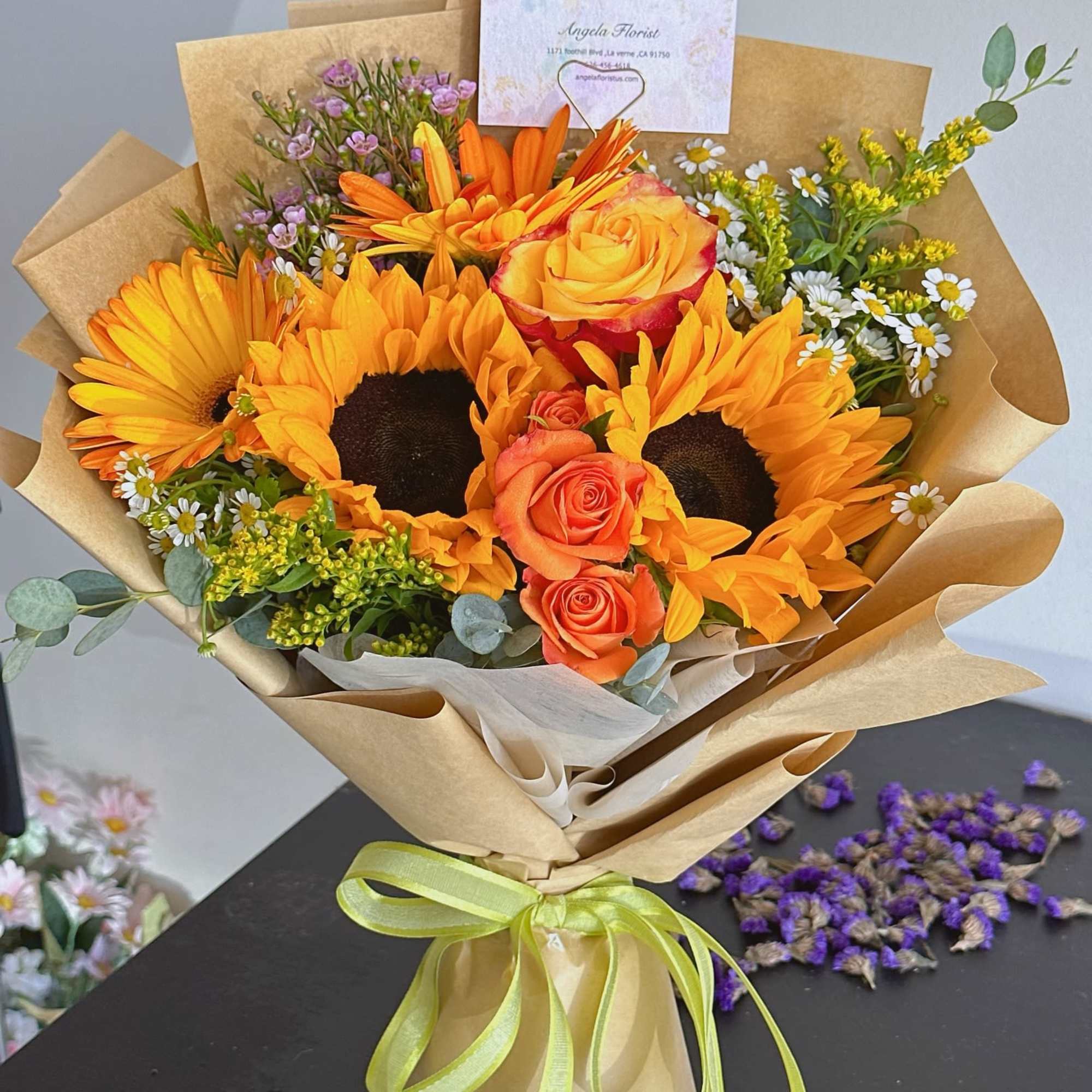 Bouquet of sunflowers and orange roses wrapped in kraft paper