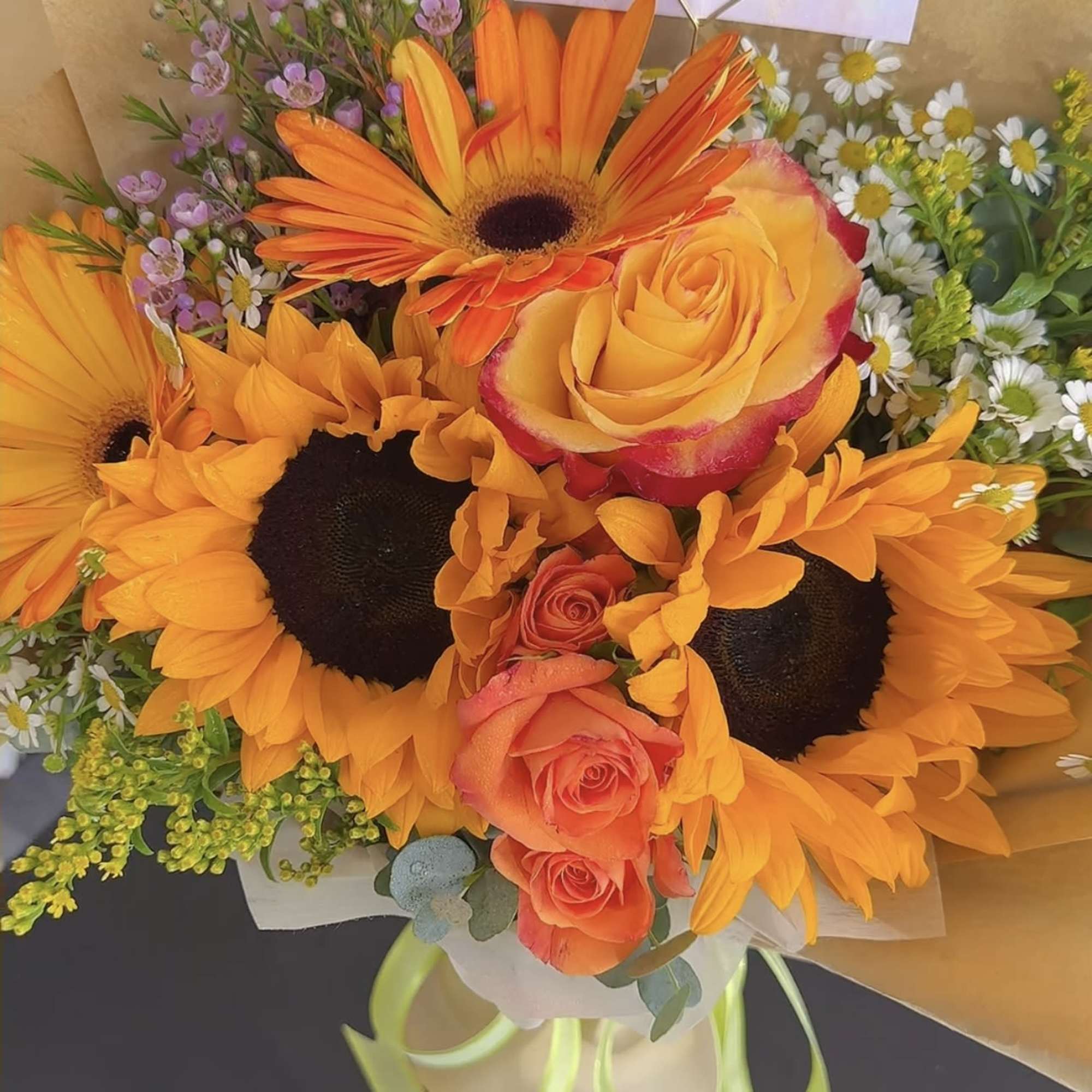 Bouquet of orange sunflowers, roses, and small white daisies