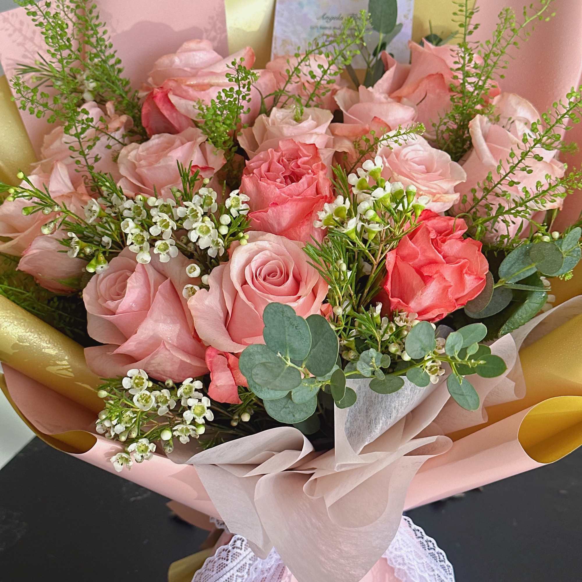 Pink rose bouquet with white filler flowers and eucalyptus in pastel wrapping