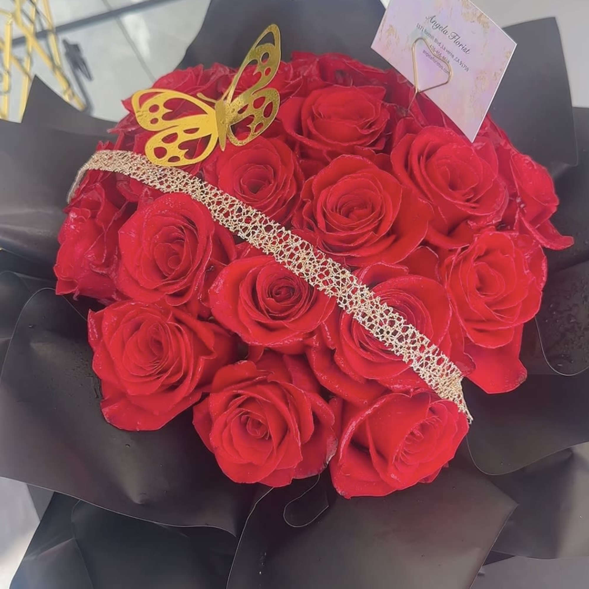 Bouquet of red roses wrapped in black paper with a gold butterfly decoration, photo 2 of 4