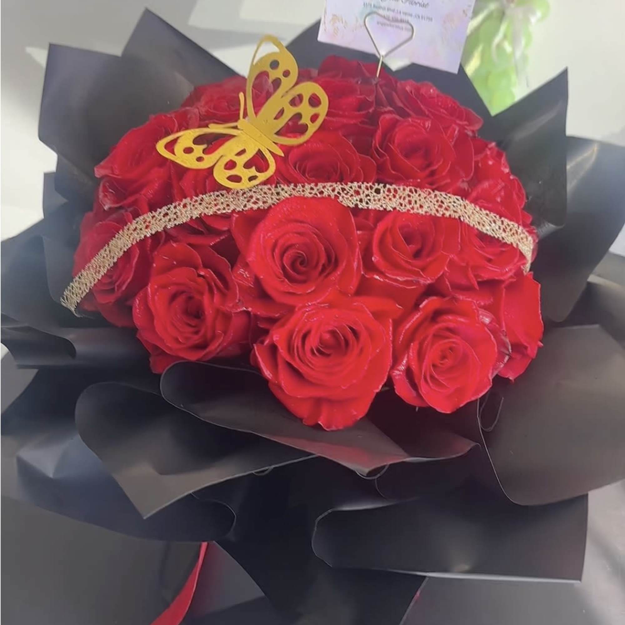 Bouquet of red roses wrapped in black paper with a butterfly decoration