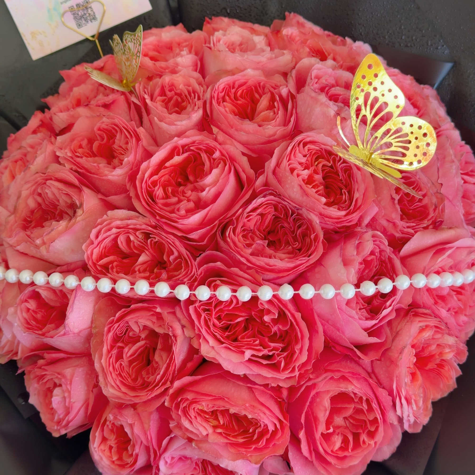 Round bouquet of pink roses with a pearl strand and gold butterfly accents