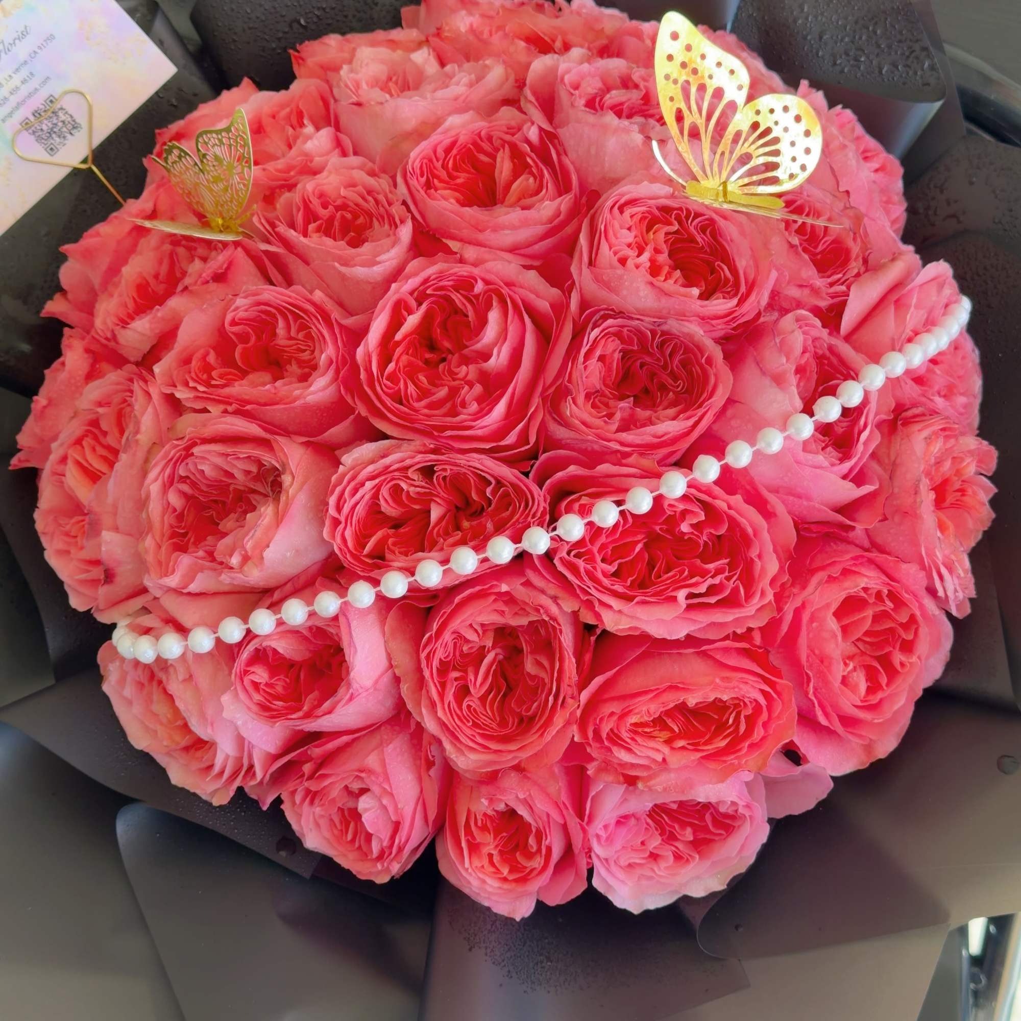 Bouquet of pink roses with butterfly picks and a pearl strand