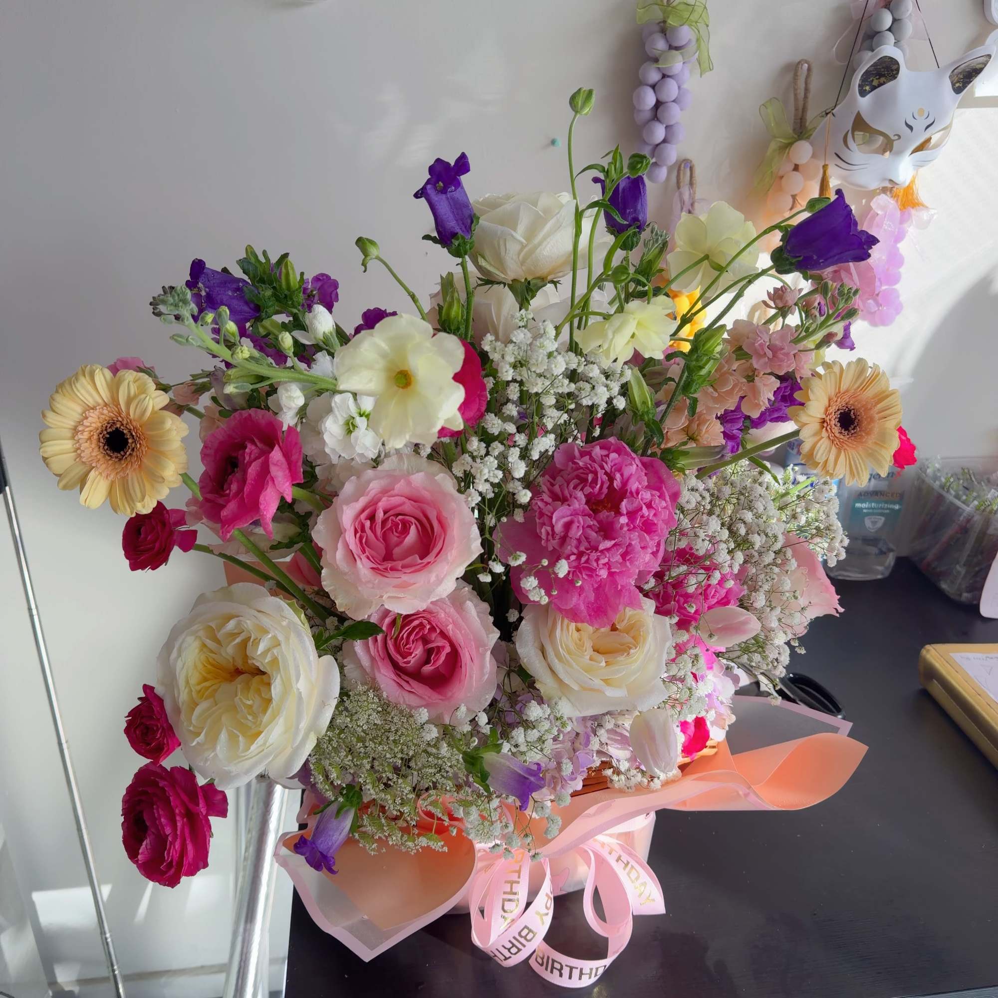 Mixed bouquet of pink, white, and purple flowers in a pink wrap