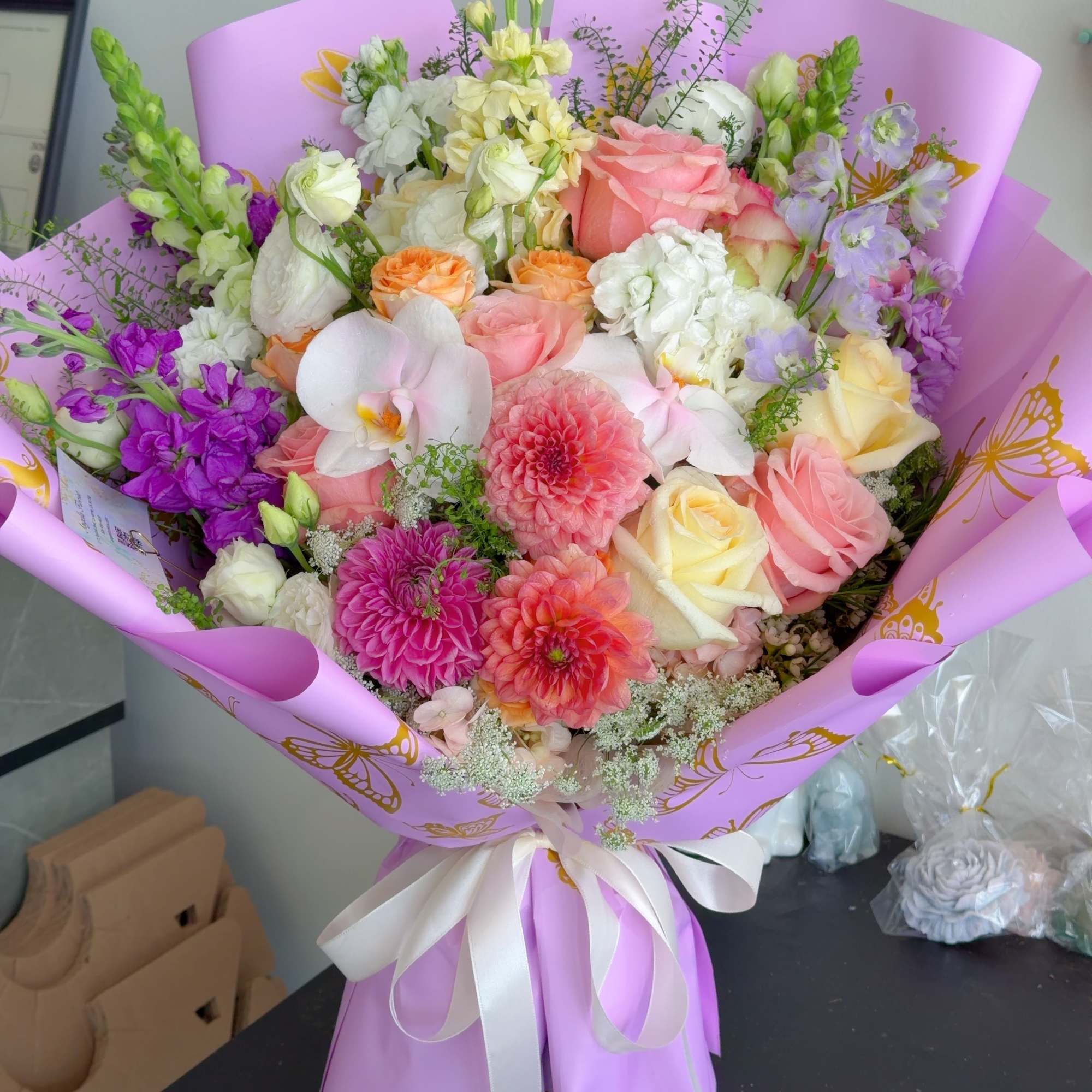 Mixed bouquet of pink, white, and purple flowers wrapped in lavender paper