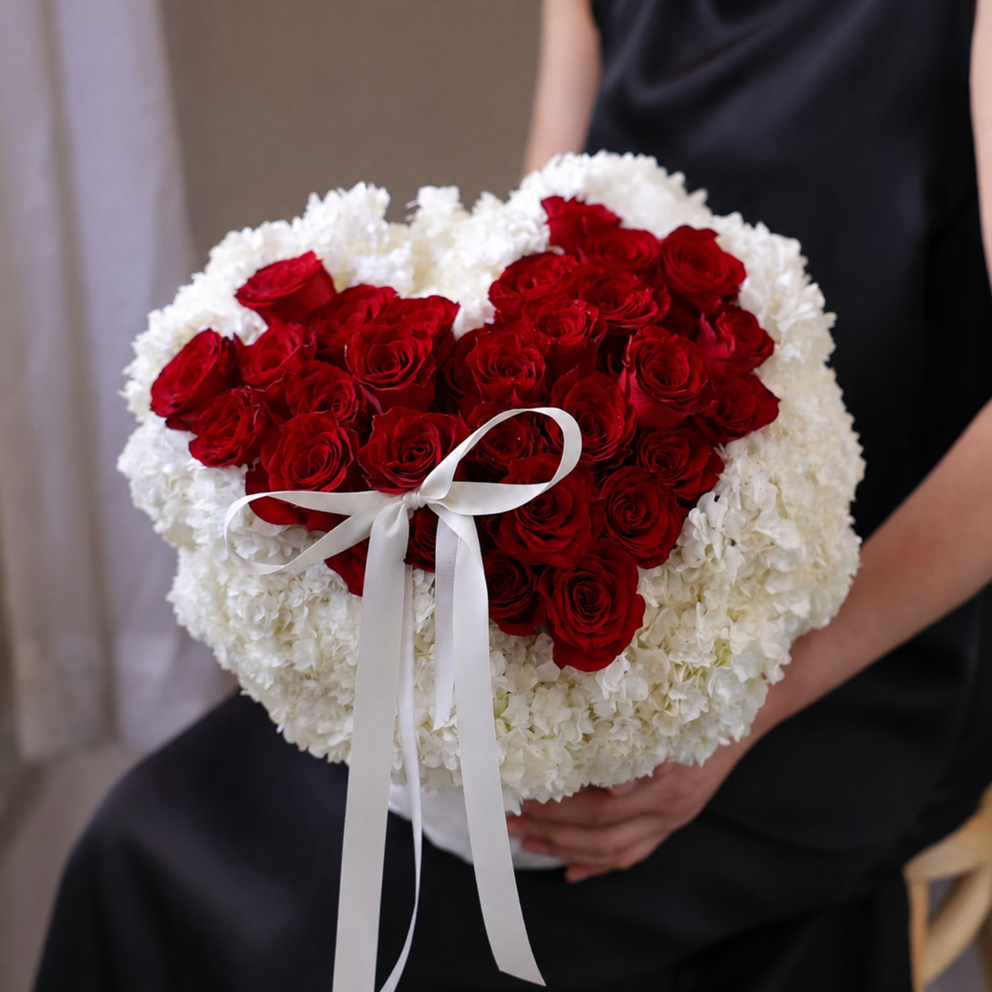 Heart-shaped bouquet of red roses and white flowers with a white ribbon
