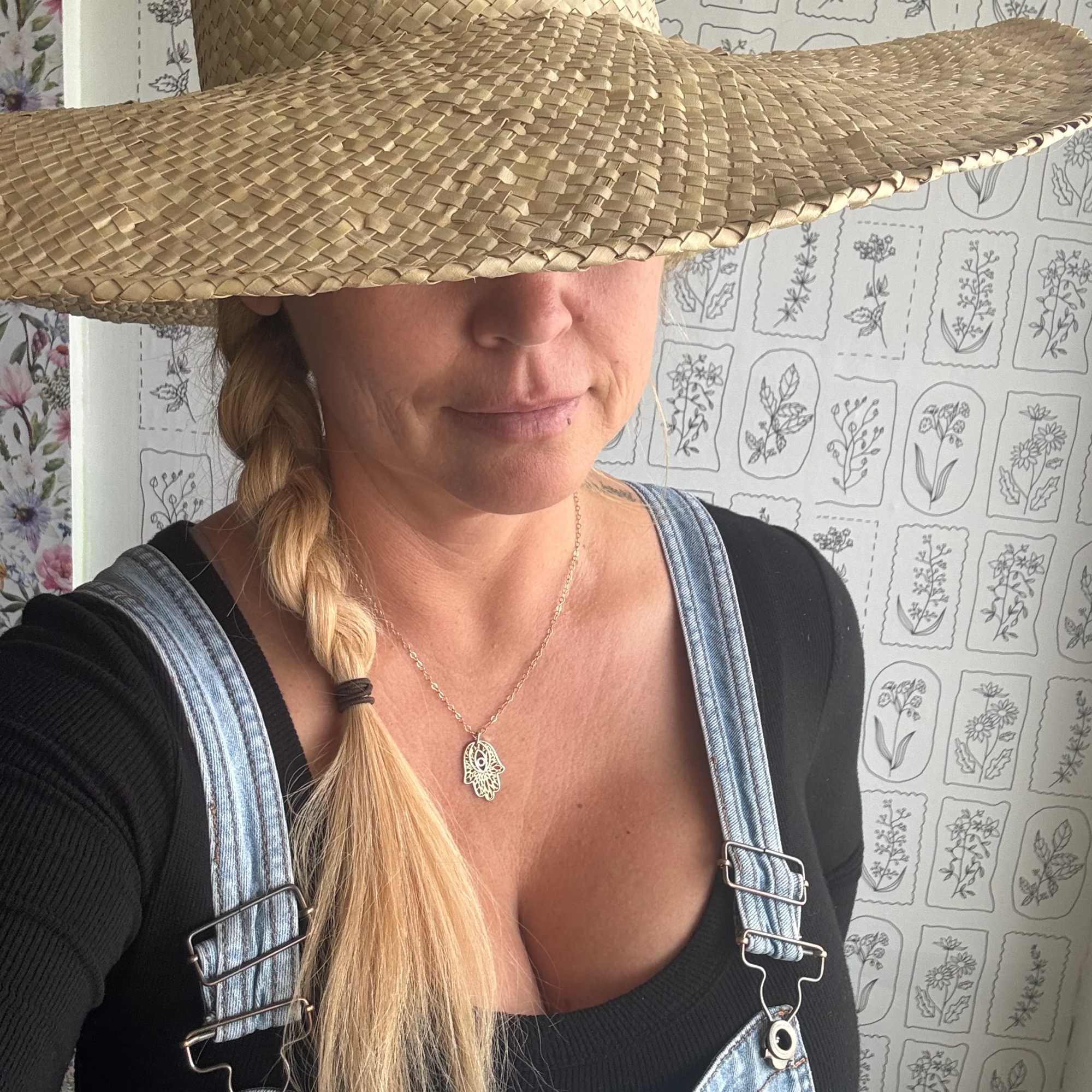 Woman wearing a large woven straw hat and denim overalls