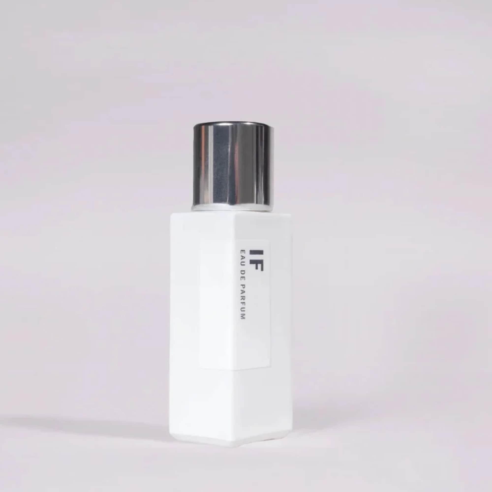 White perfume bottle with a silver cap on a pale background