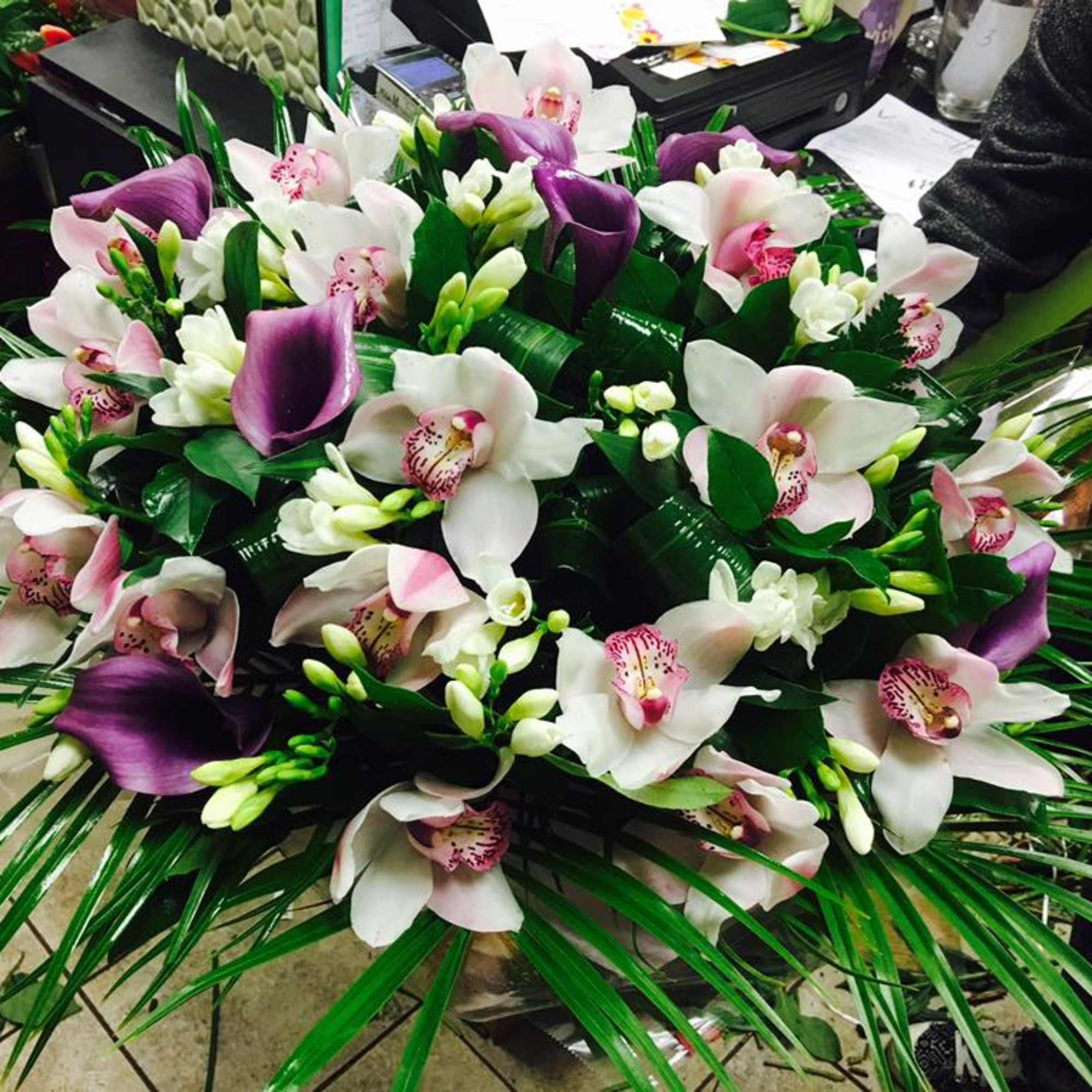 Arrangement of white and purple orchids with long green leaves