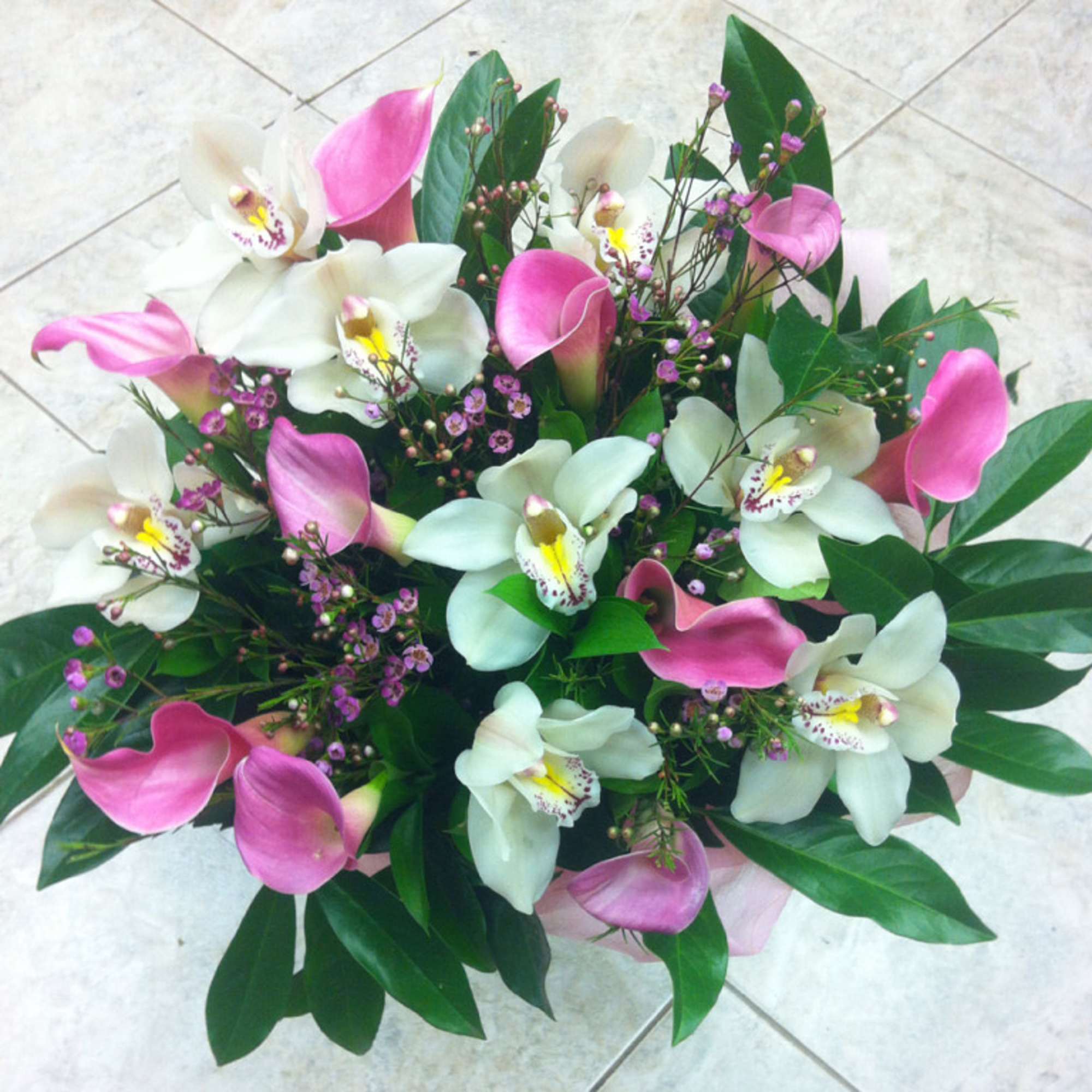 Bouquet of pink calla lilies and white orchids with greenery