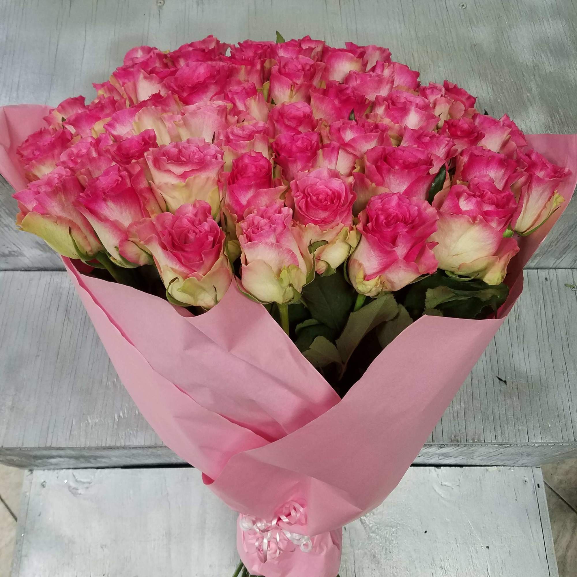 Bouquet of pink-and-white roses wrapped in pink paper