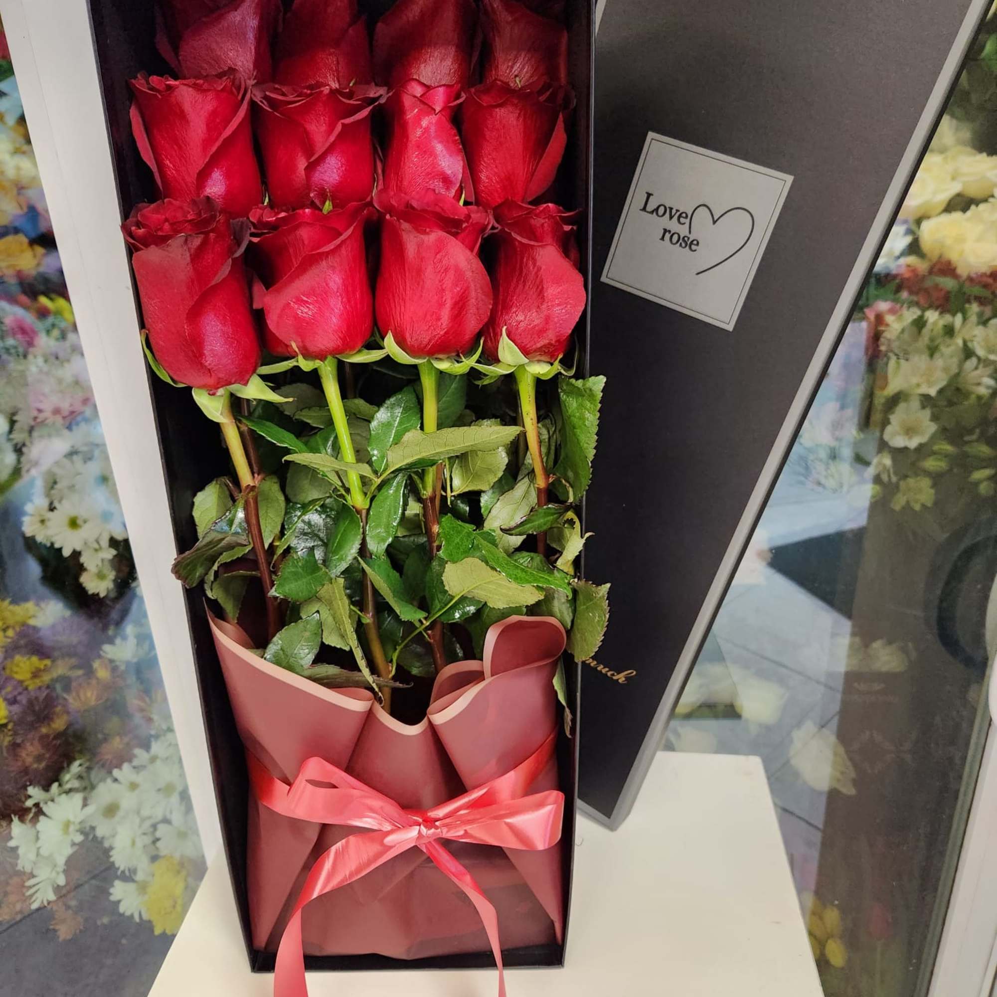 Boxed bouquet of red roses with a pink ribbon