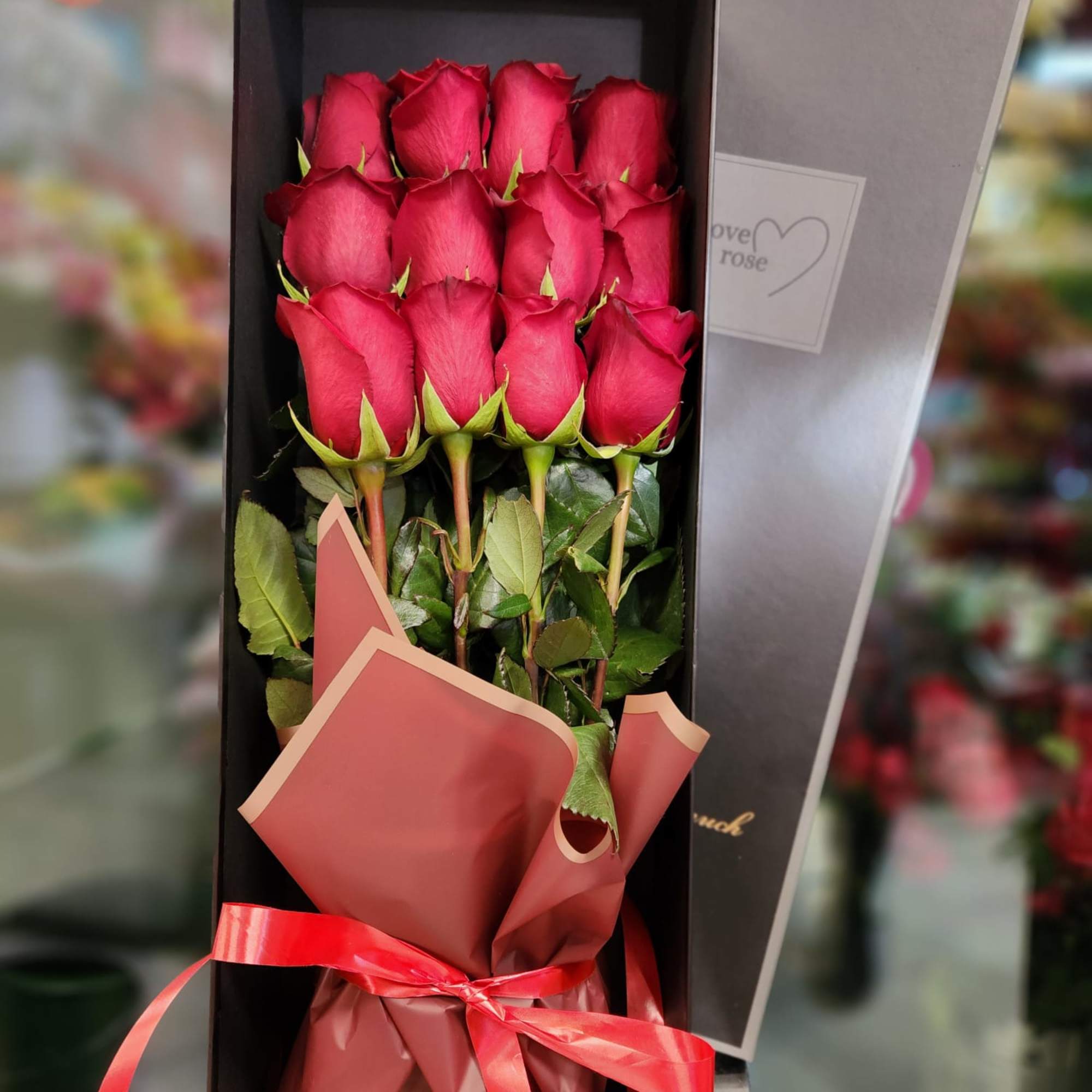Boxed bouquet of red roses tied with a red ribbon