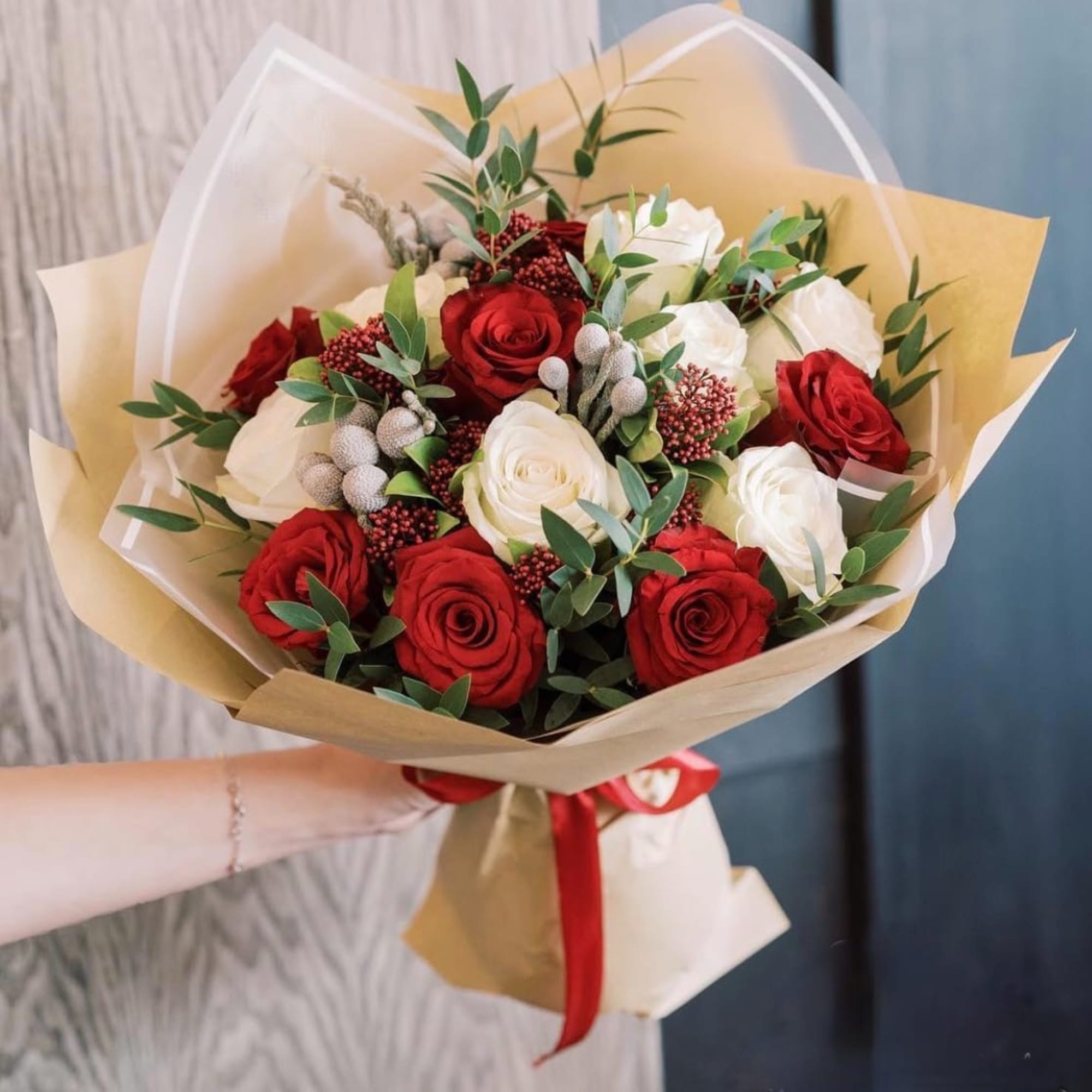 Bouquet of red and white roses wrapped in tan paper with a red ribbon