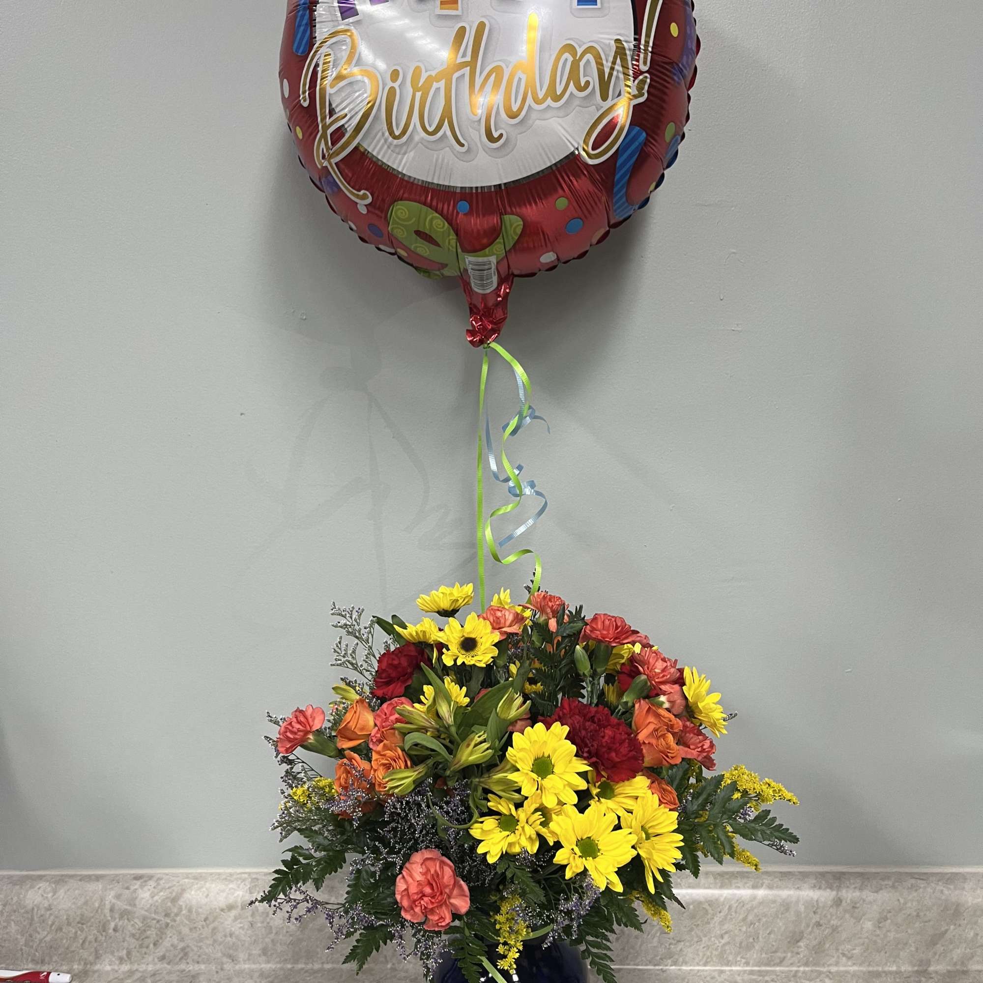 Blue vase with rainbow of colors of fresh flowers and a mylar