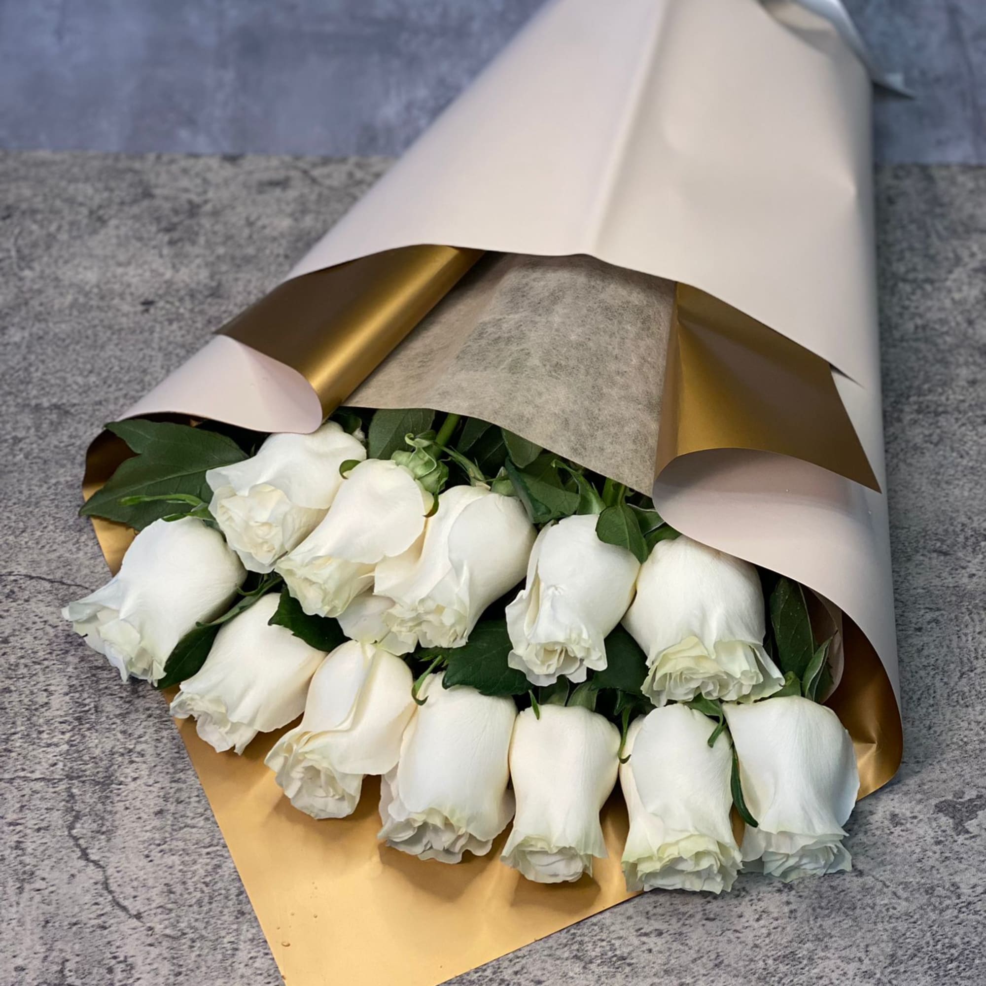 Bouquet of white roses wrapped in white and gold paper