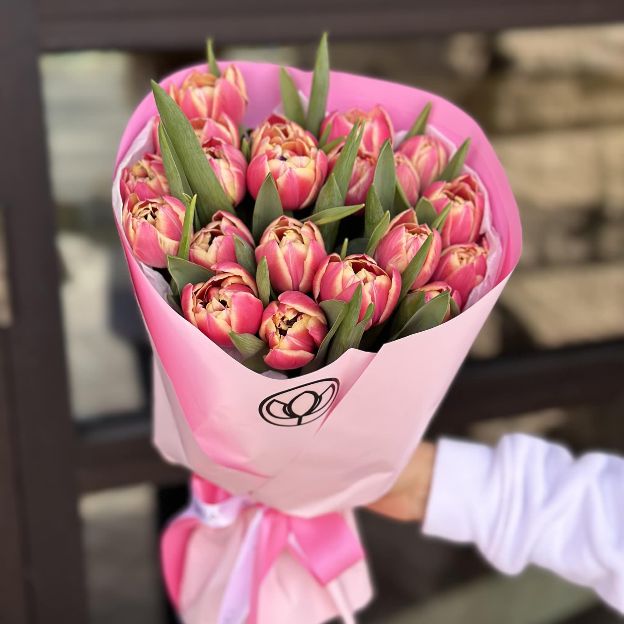 Pink tulip bouquet wrapped in pink paper with a ribbon
