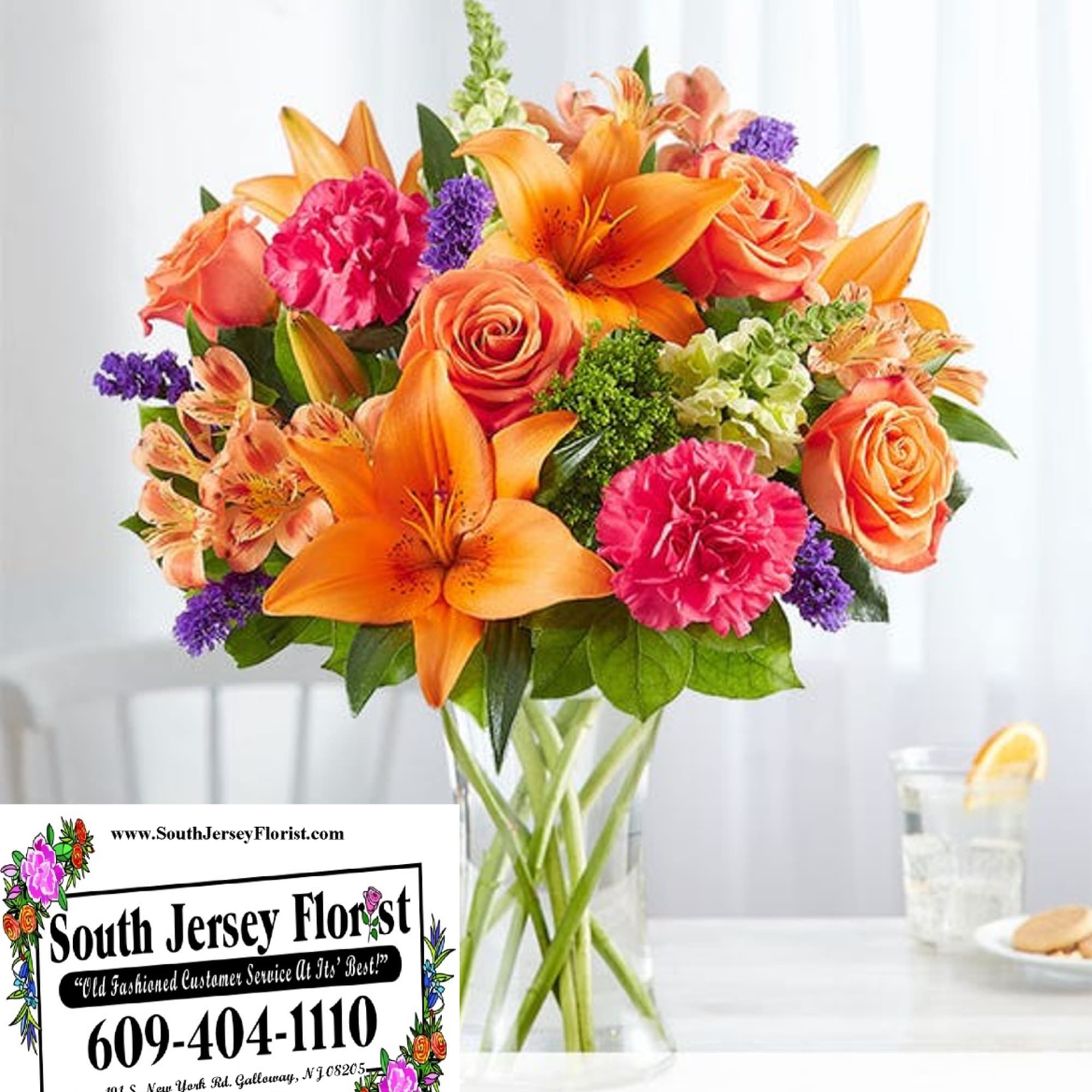 Orange lilies and roses in a clear glass vase
