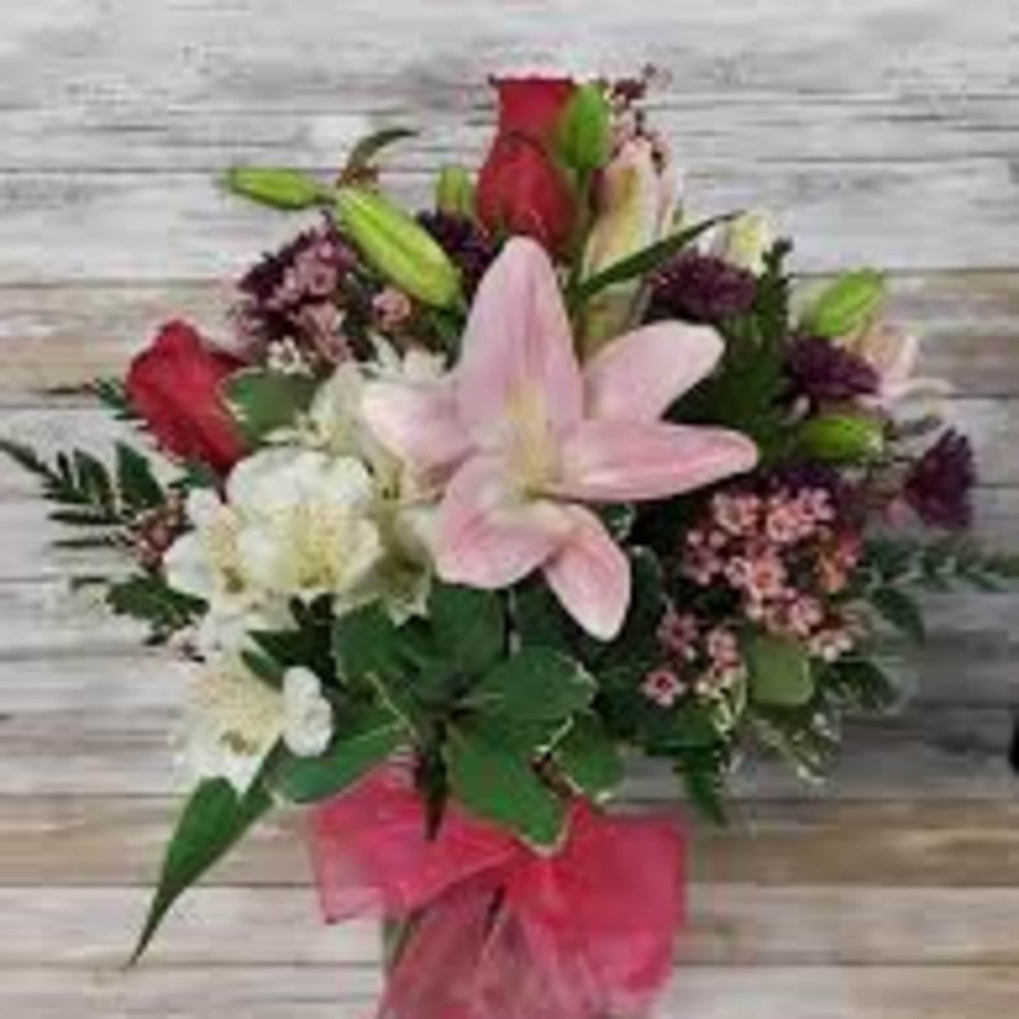 Mixed bouquet with pink lily, red roses, and white blooms tied with a pink bow