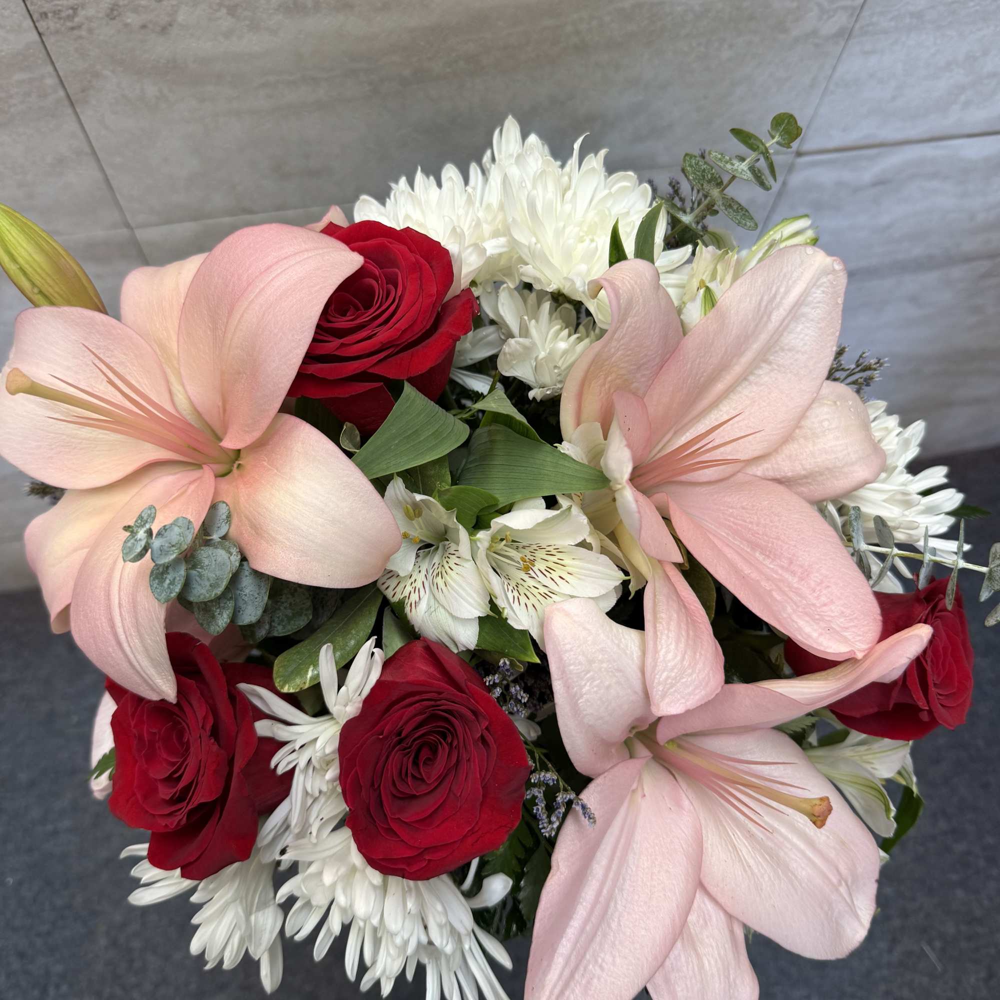 Bouquet of pink lilies, red roses, and white daisies