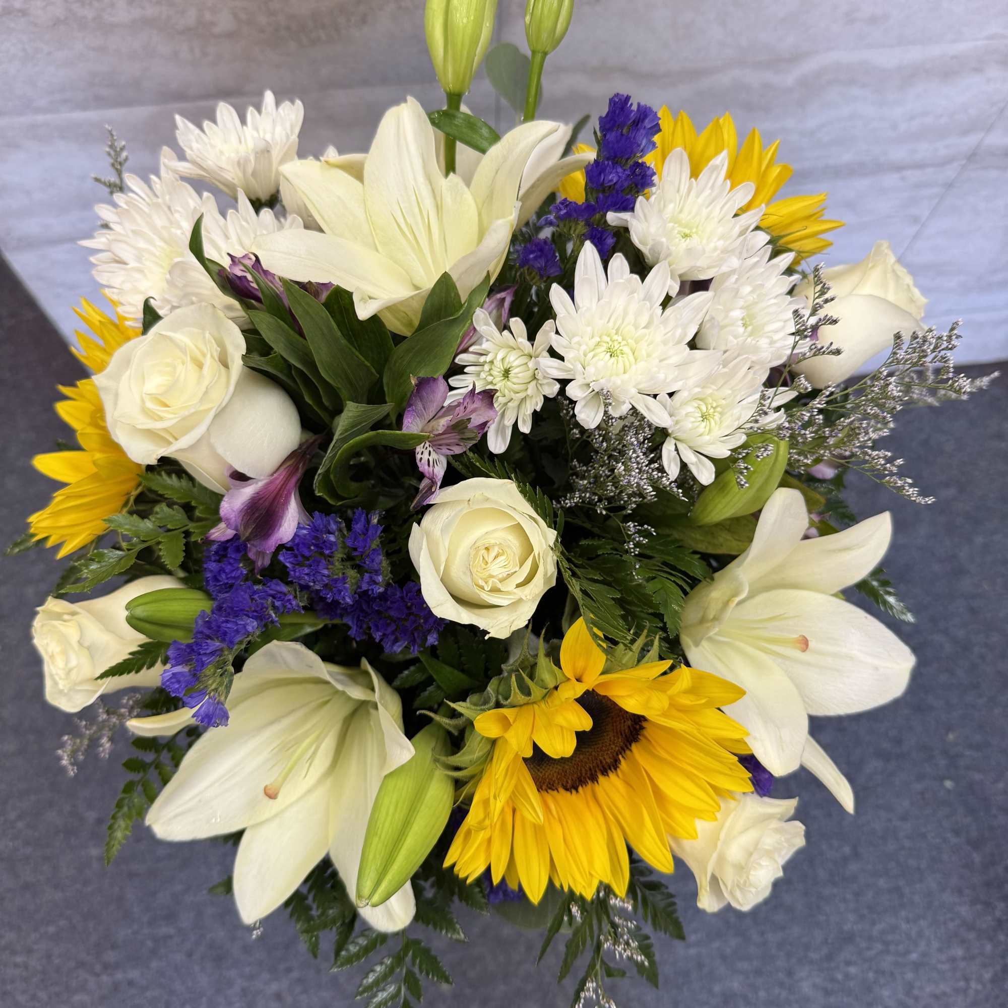Bouquet of white lilies, roses, sunflowers, and purple filler flowers