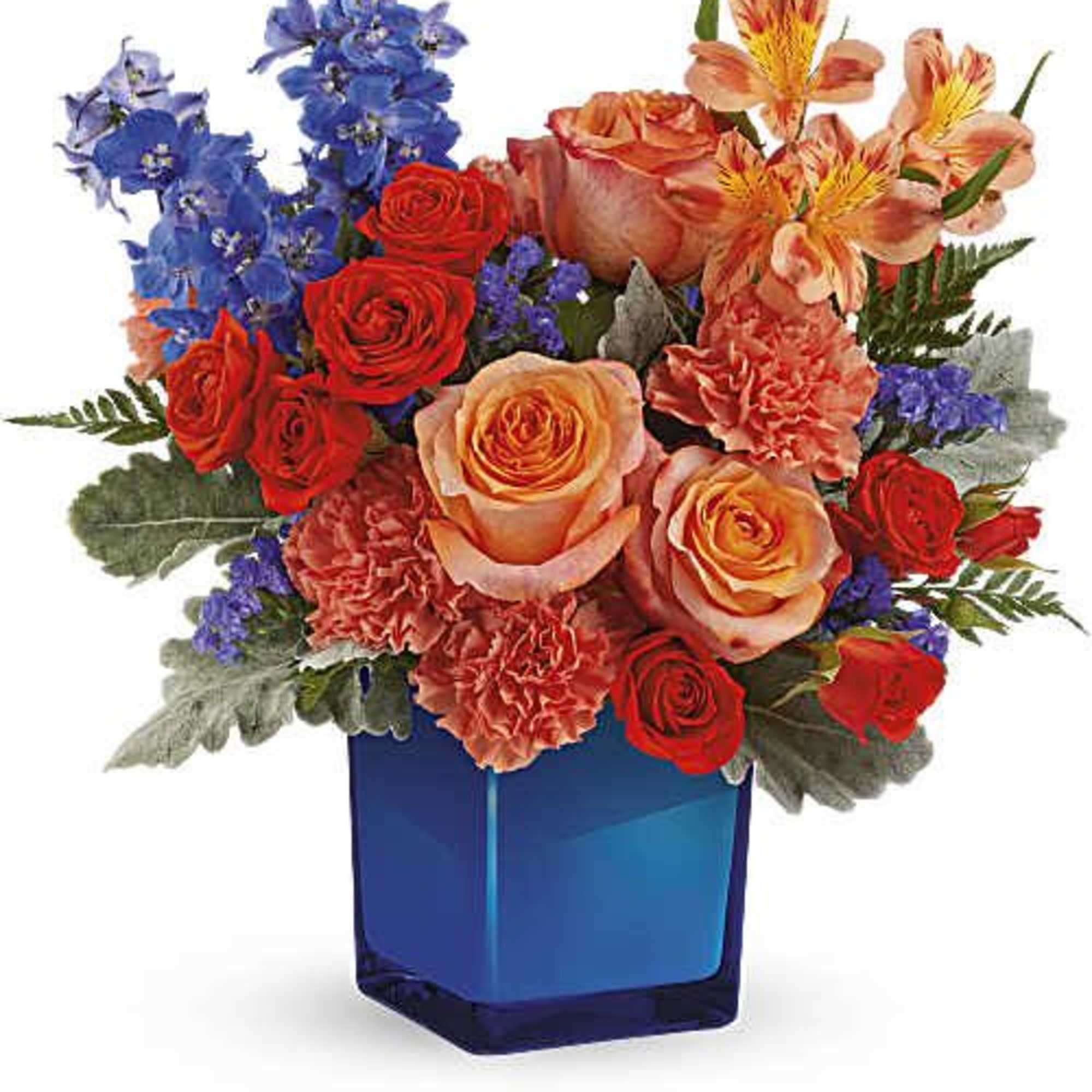 Mixed bouquet of roses, carnations, and blue flowers in a blue glass vase