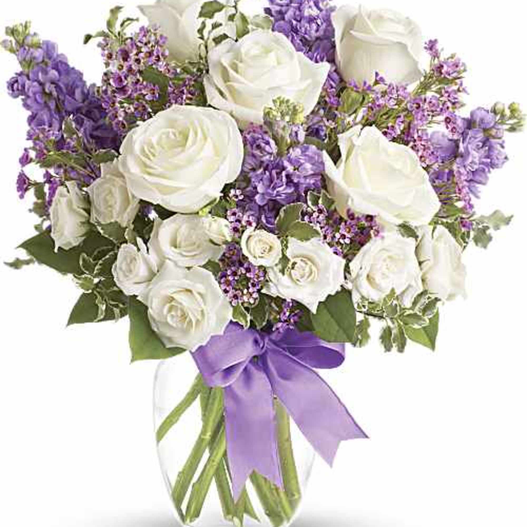 White roses and purple flowers in a clear glass vase with a lavender ribbon