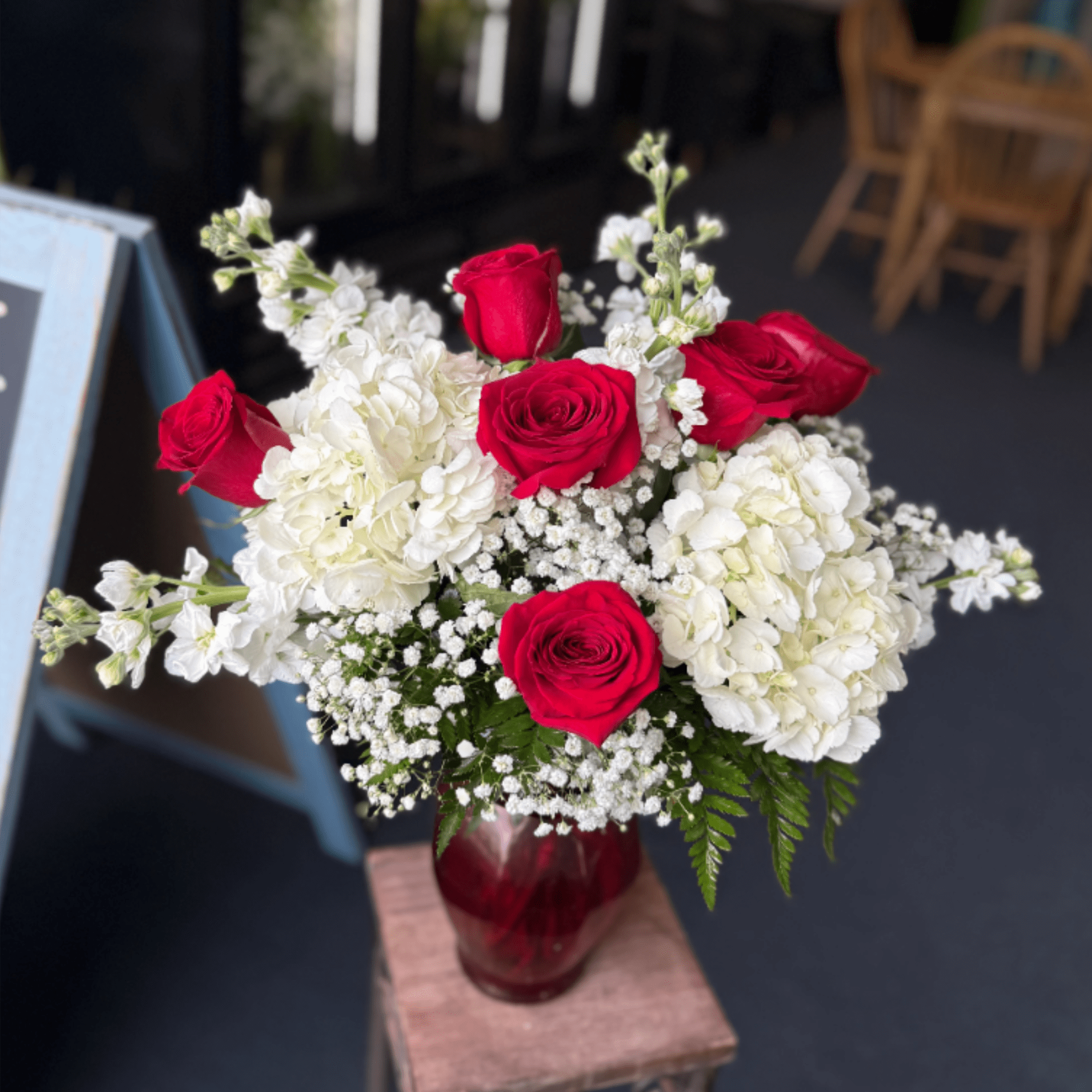 Vivid red roses and lush white hydrangeas with airy white fillers in