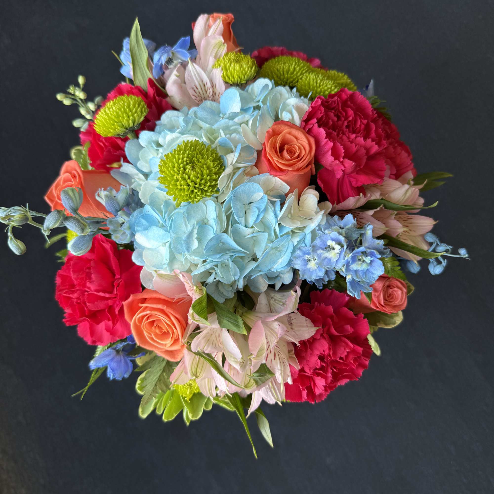 Colorful bouquet with blue hydrangeas, pink carnations, and orange roses