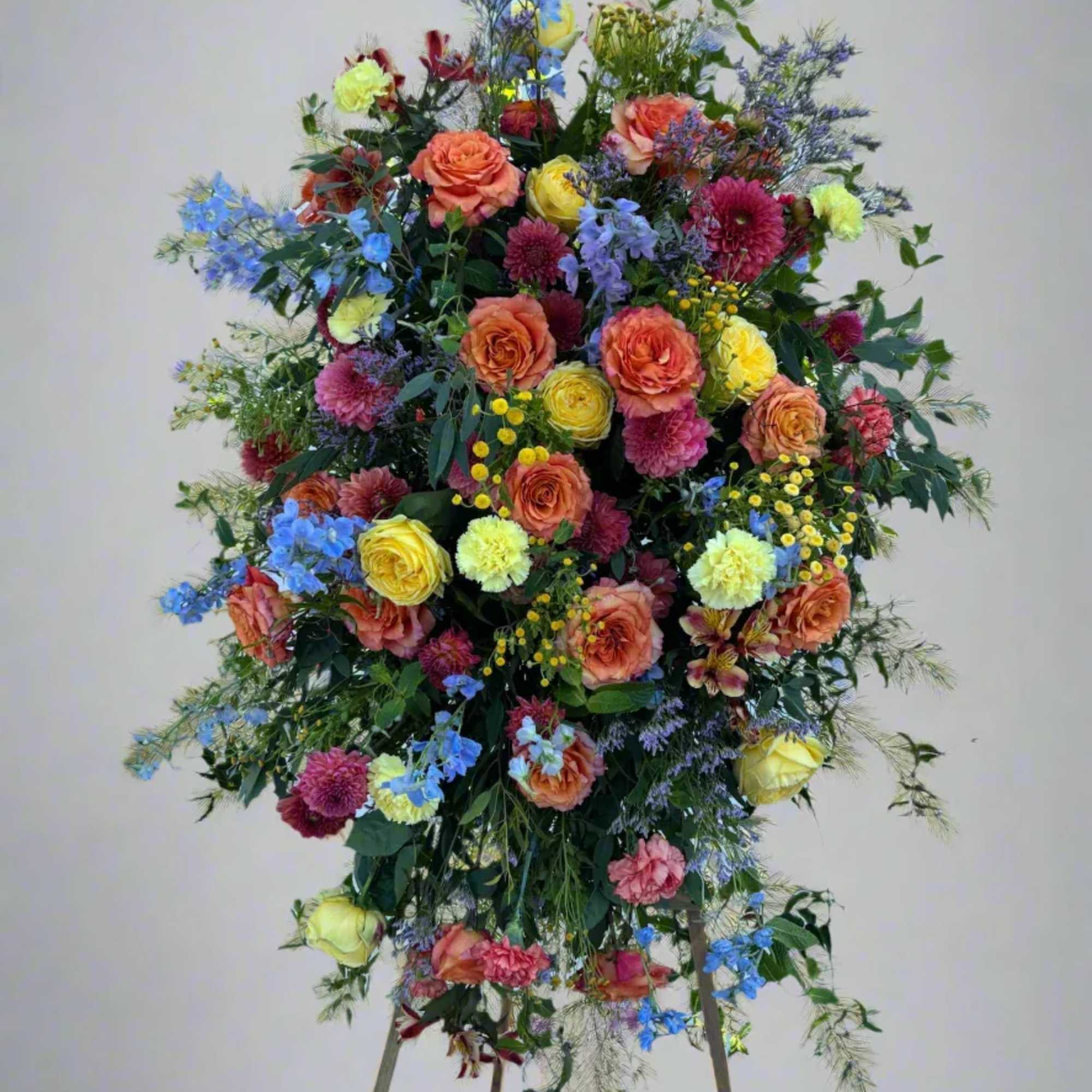 Tall standing floral spray with multicolored roses and mixed blooms