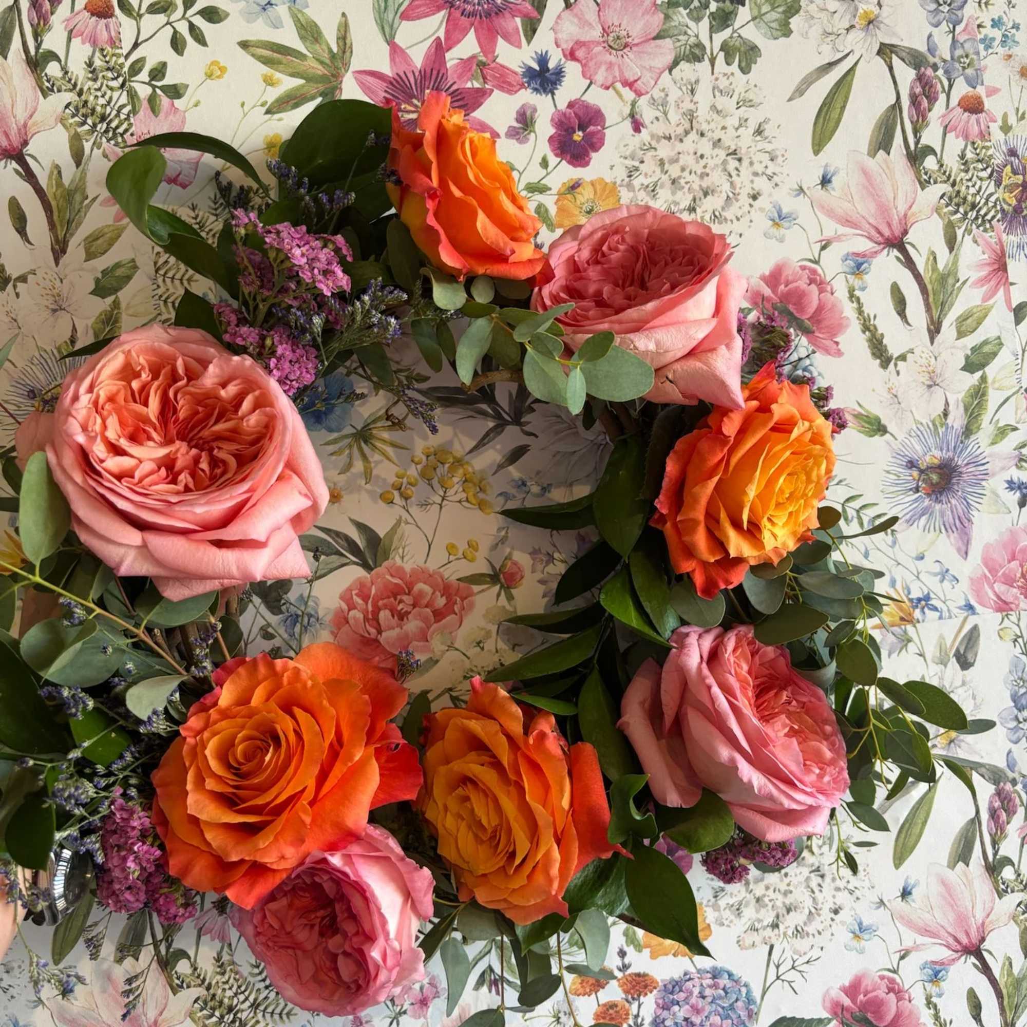 Floral wreath with pink and orange roses on a patterned background