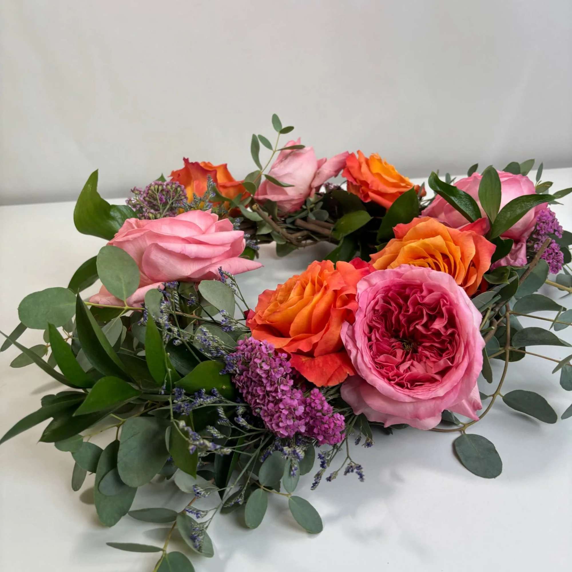Floral wreath with pink and orange roses and purple filler flowers