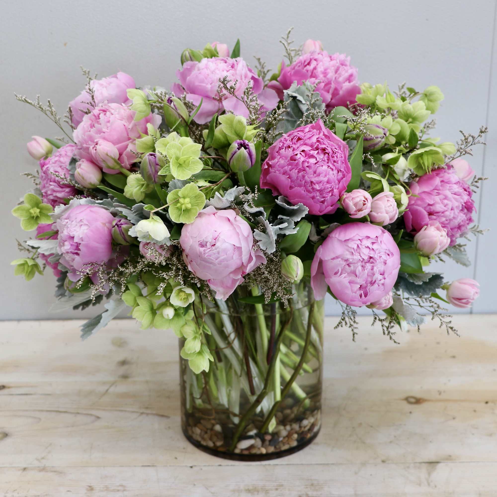 Peonies, tulips, and seasonal greens in our glass vase. 